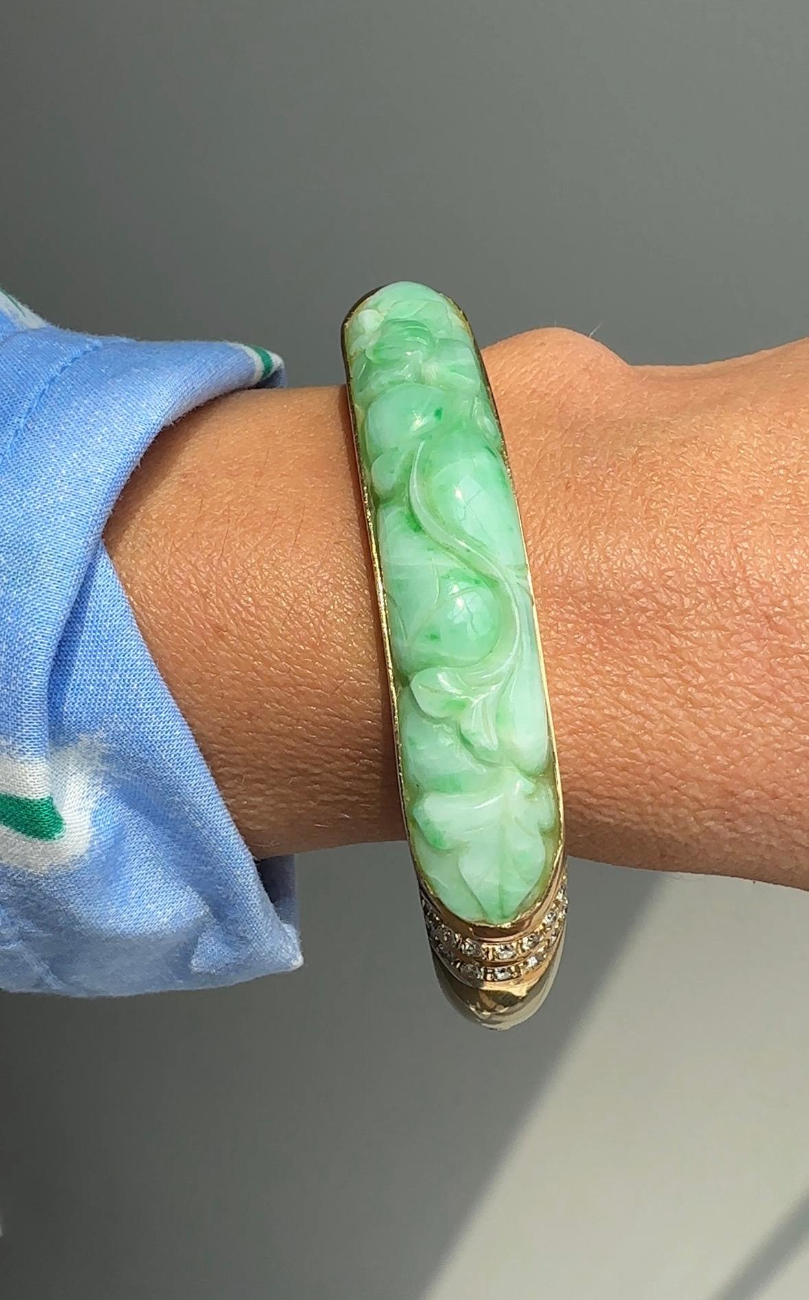 This striking mid-twentieth century bangle is chic modern design that contains a late 19th century jade carving. The vibrant apple green and white jade carving is presented in 14 karat yellow gold bangle with brilliant cut diamond accents.