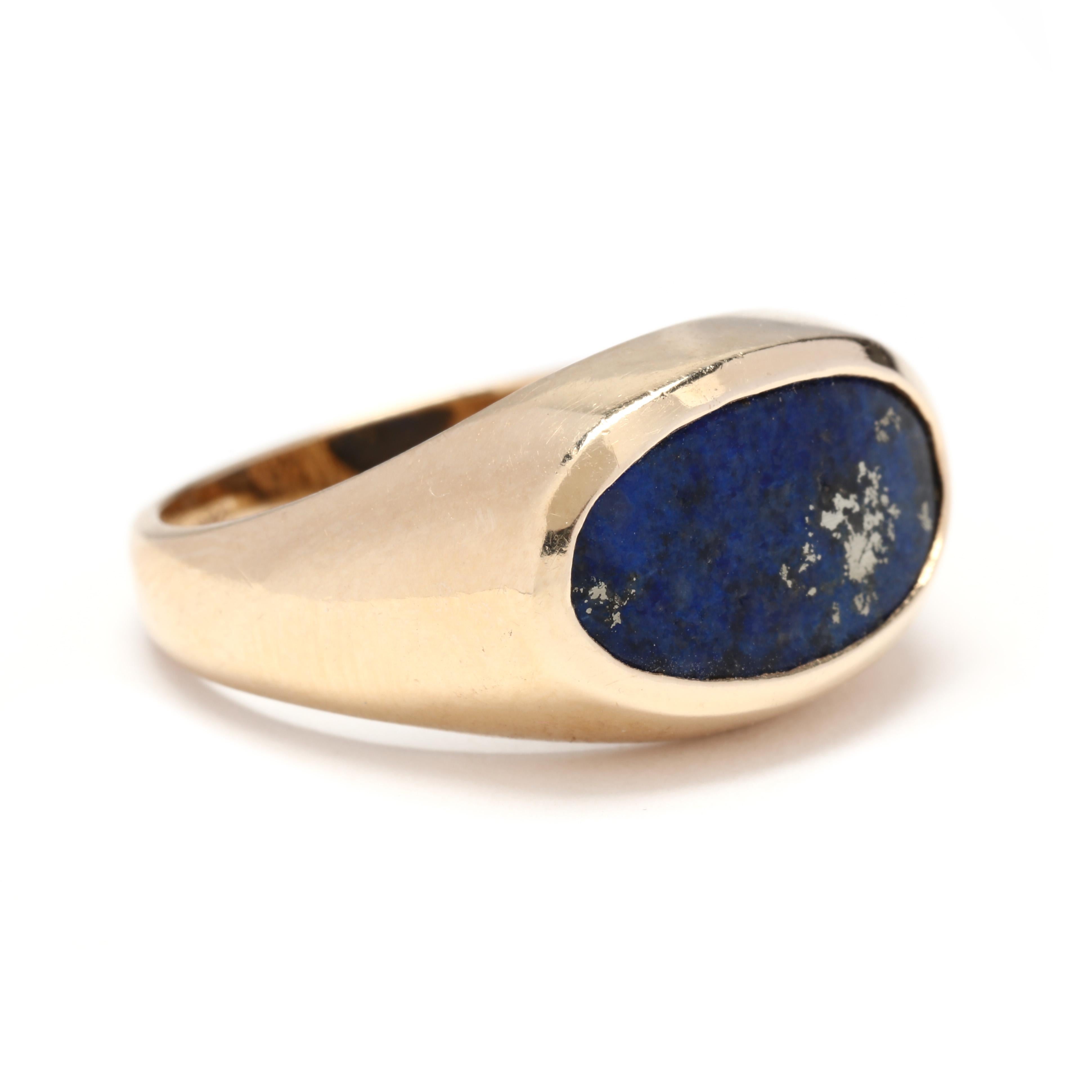 A vintage 14 karat yellow gold lapis signet saddle ring. This ring features a bezel set, horizontal oval lapis that is slightly curved and with a tapered shank. This lapis is of a dark royal blue color with an attractive patch of pyrite