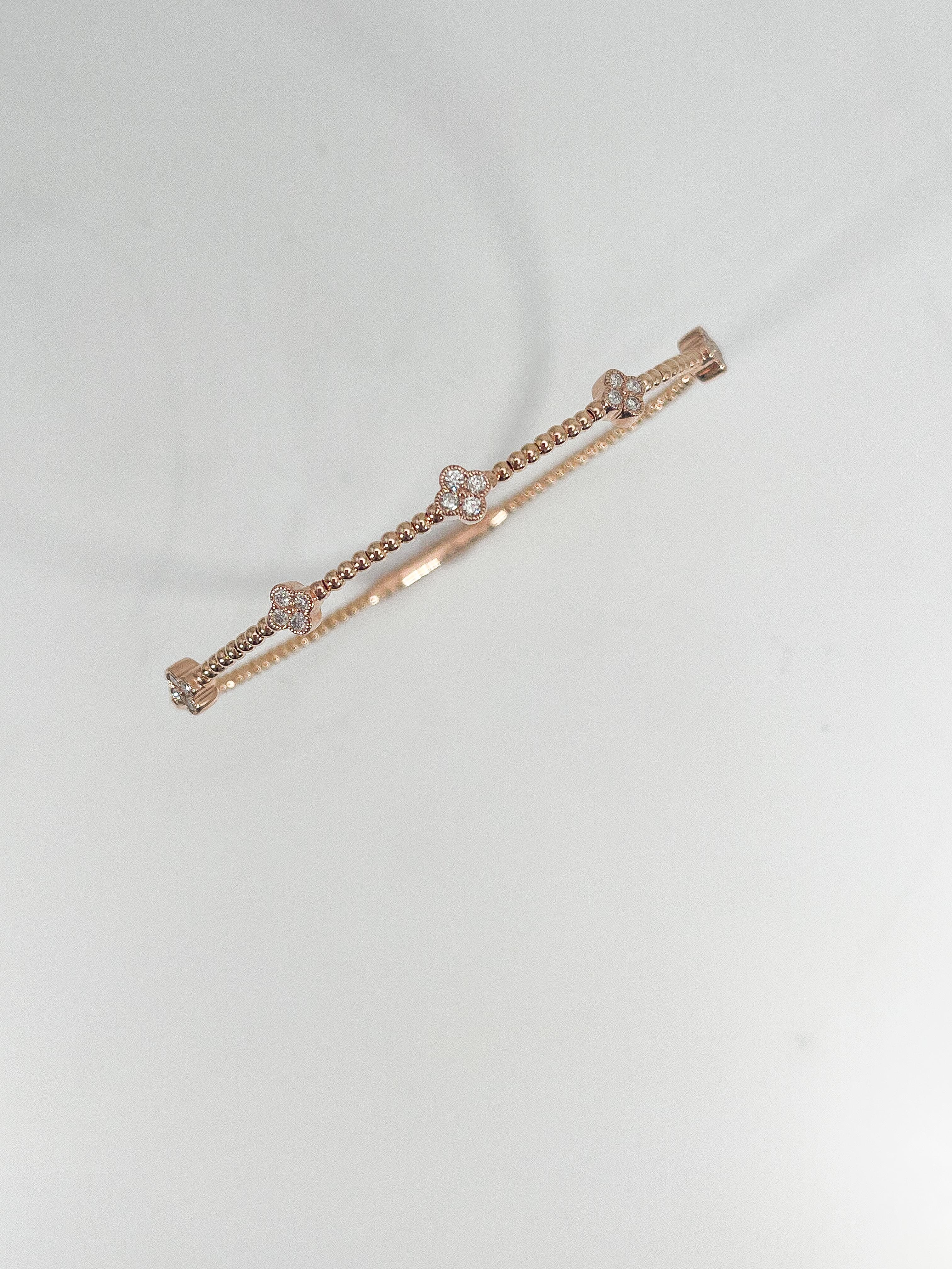 14k rose gold .32 CTW diamond cluster flex bangle. The diamonds in this bracelet are all round, the width is 5 mm, the inside diameter is about 4 inches, and it has a total weight of 5.32 grams.