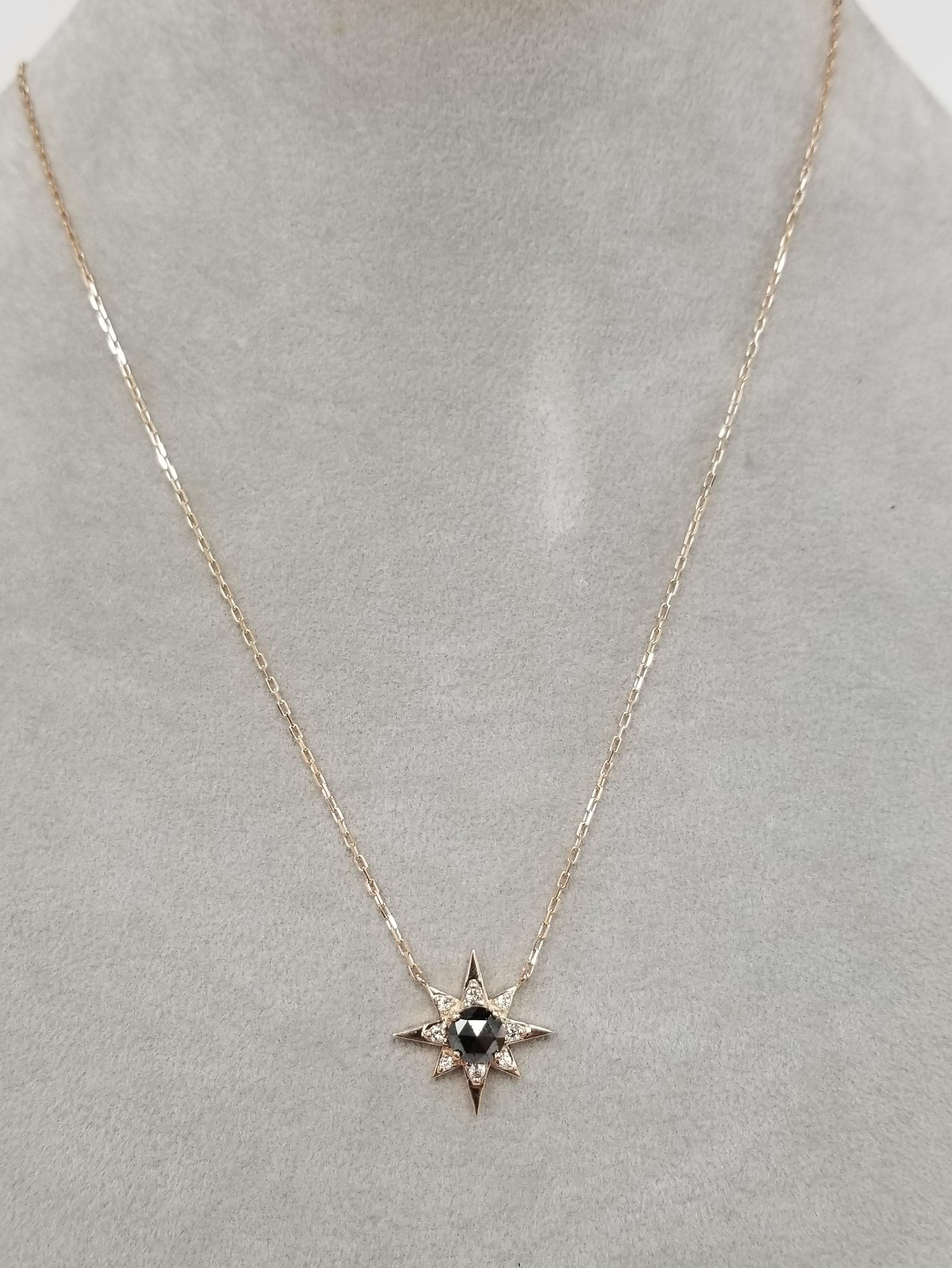 14k rose gold diamond star burst with black and white diamonds, containing 1 faceted cut black diamond weighing 1.00cts. and 8 round full cut diamonds weighing .25pts. on a 18 inch chain.
