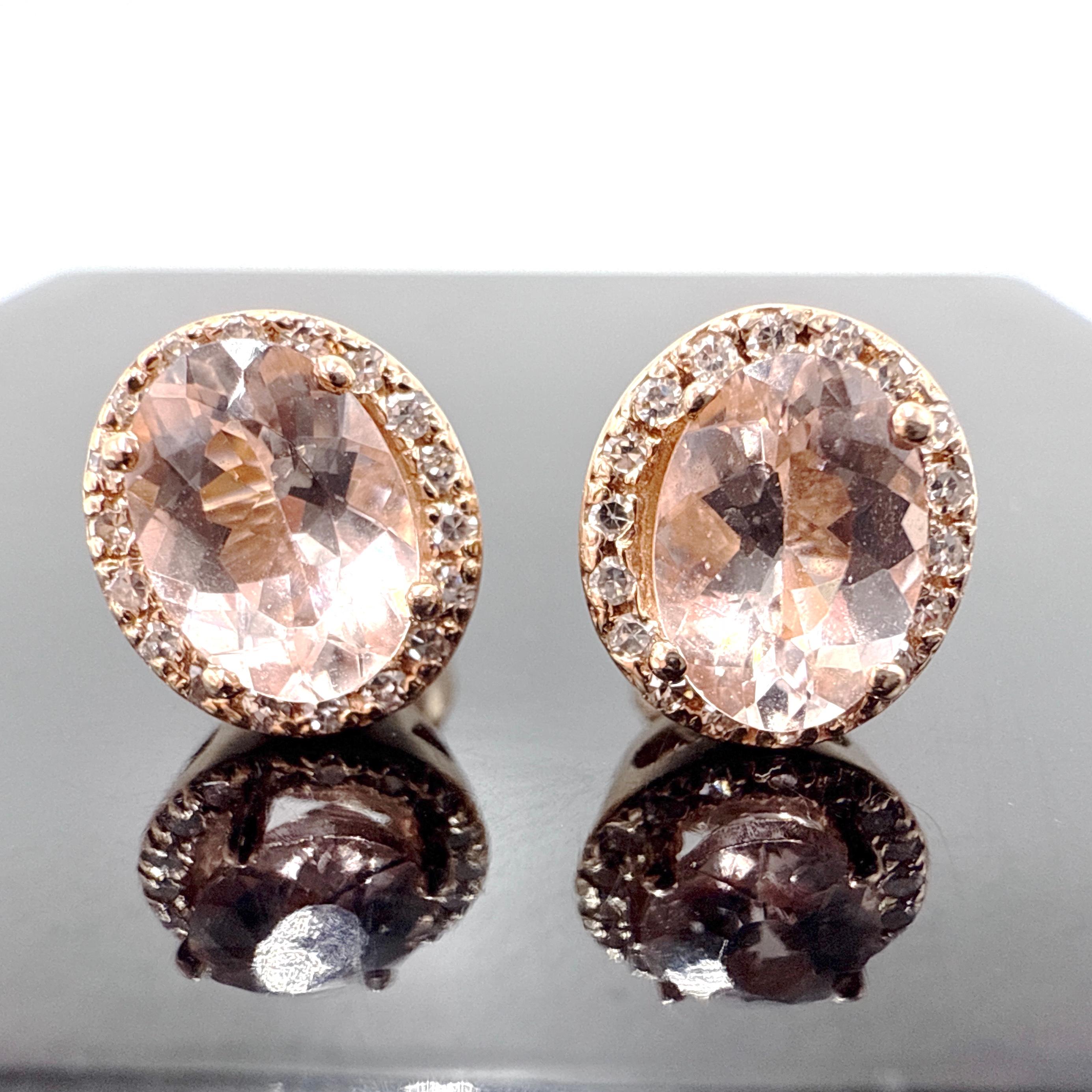 Questo paio di orecchini a perno in oro rosa 14K presenta pietre centrali di morganite dal taglio ovale incorniciate da gruppi di diamanti. Ogni orecchino è realizzato con una montatura centrale a quattro griffe circondata da diciotto diamanti