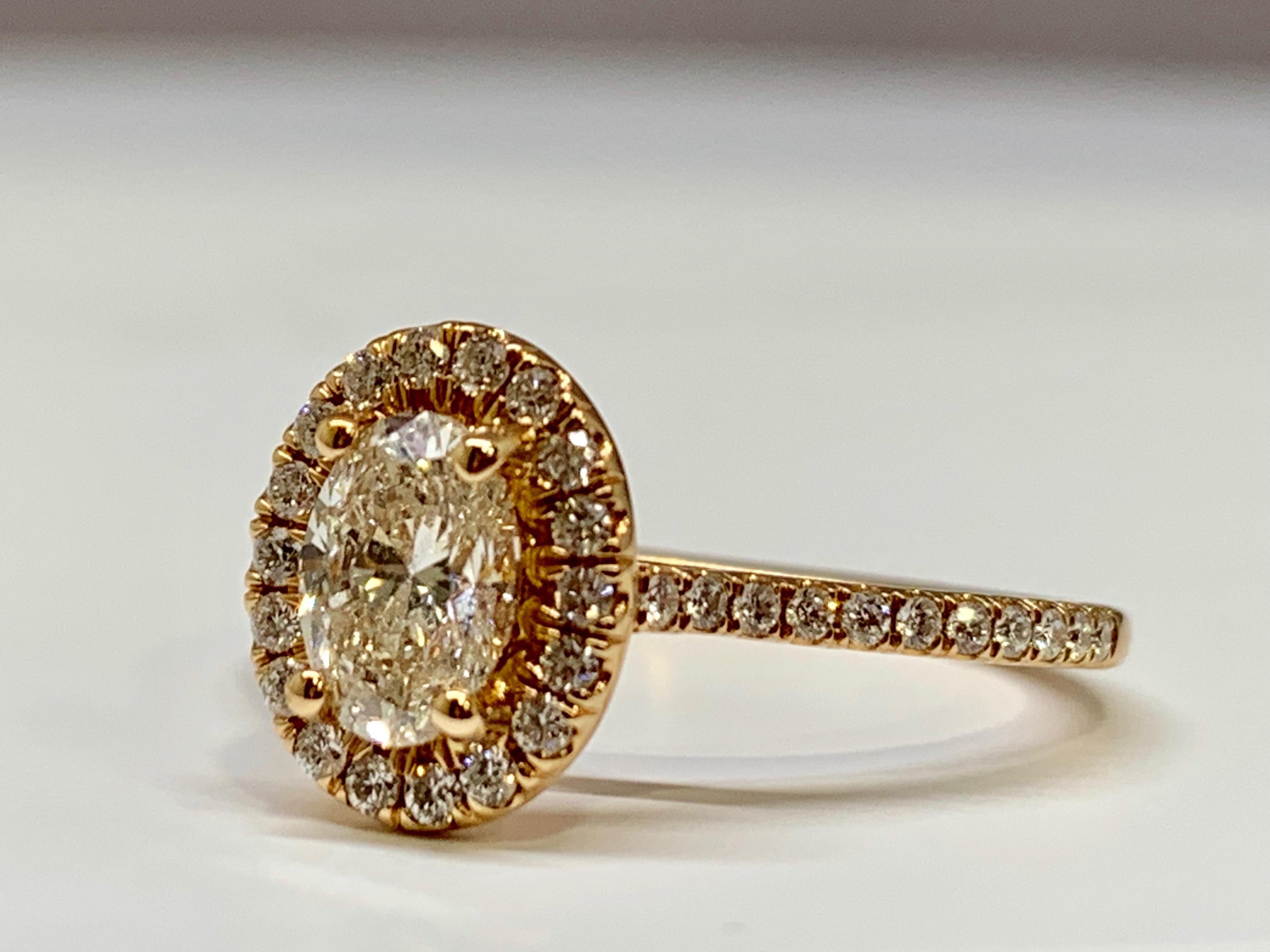 This beautiful engagement ring is made of 14k rose gold and features a GIA certified 0.70 carat G SI1 oval-shaped center diamond. The gorgeous pave halo mounting holds an additional 0.32 carats of round diamonds. This ring will be shipped with its