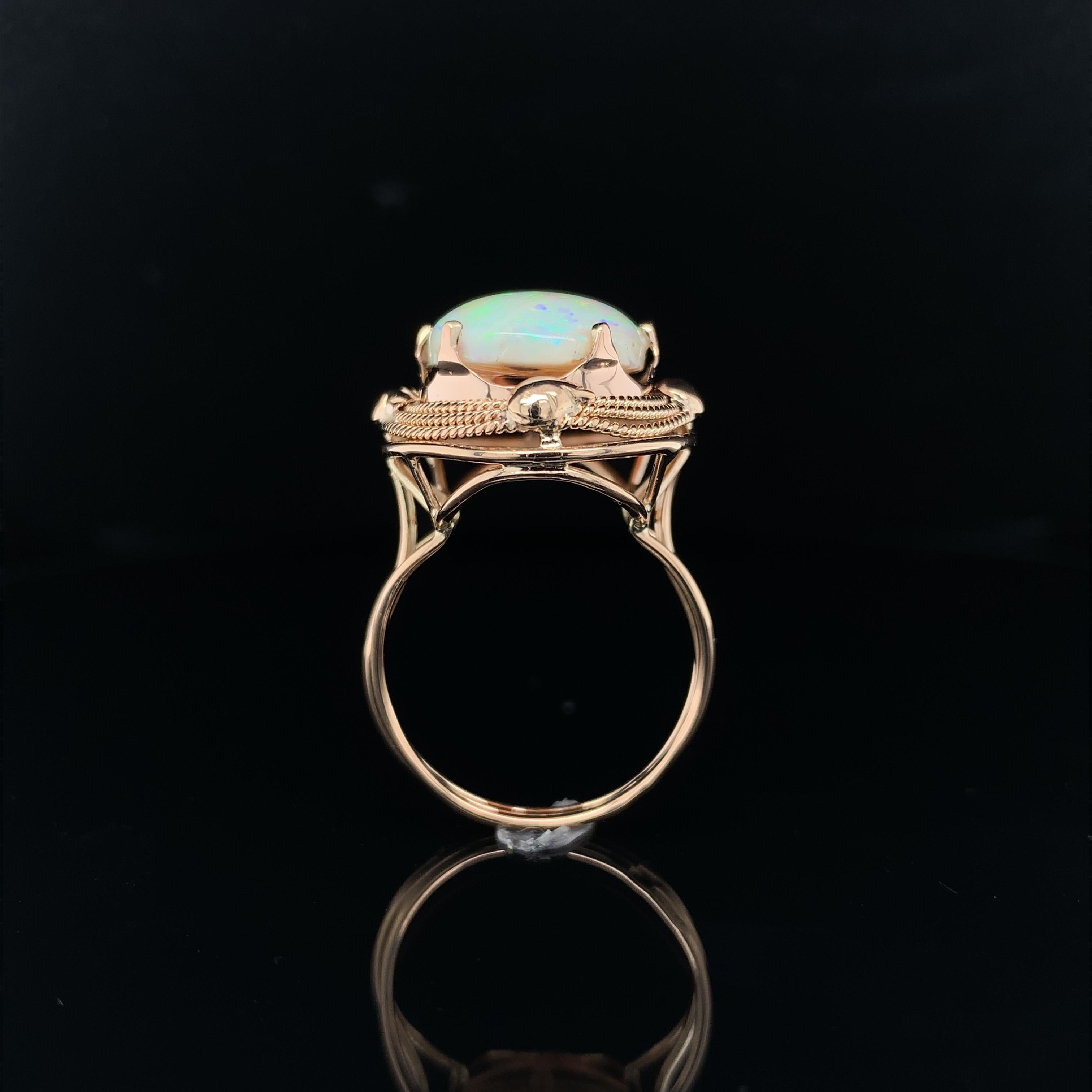 Vintage 14K rose gold 6.05 carat opal ring. The genuine natural Australian opal measures about 17mm x 12mm. The opal is freshly polished and has primarily pink and green play of color, with flashes of all colors. The ring is hand wrought hand made