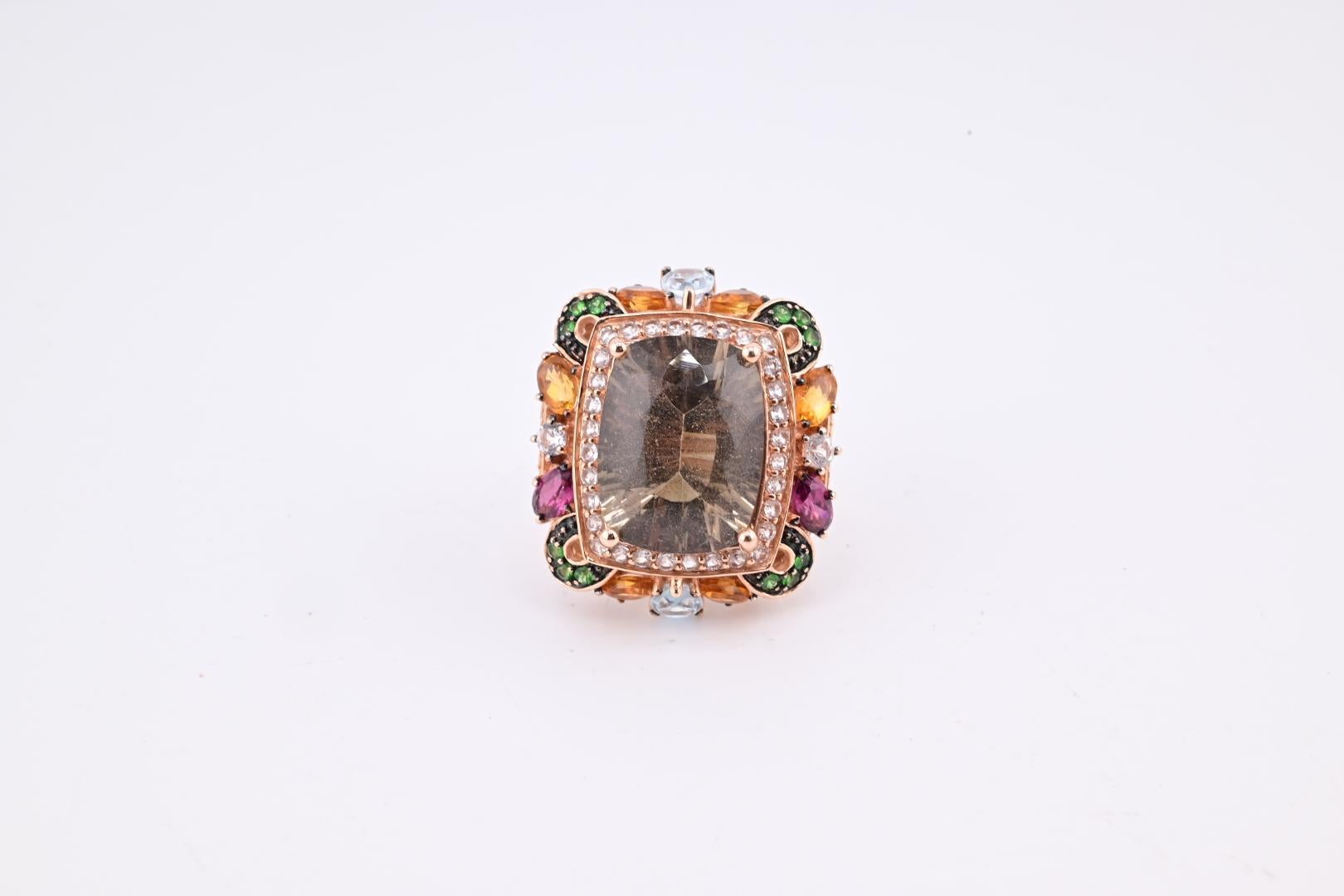This is a striking quartz Levian ring. It is crafted from fine 14k rose gold. The primary stone is a champagne-colored quartz. The design features an array of colorful gemstones surrounding the central quartz. The setting includes intricate