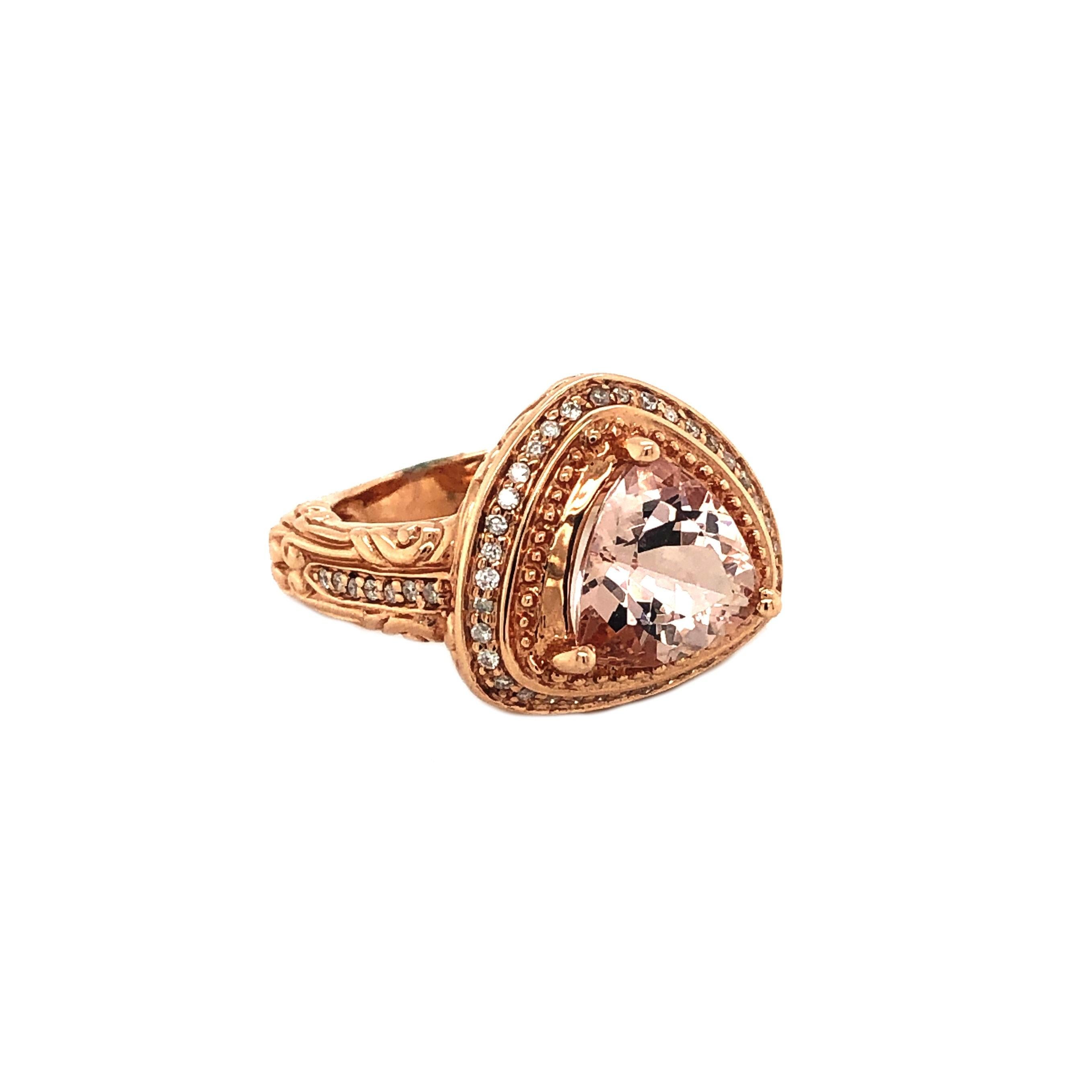 This is a gorgeous natural morganite and diamond vintage ring set in solid 14k rose gold. The natural 2.70 Ct trillion cut morganite has an excellent peachy pink color and is surrounded by a halo of round cut white diamonds. The ring is stamped 14k
