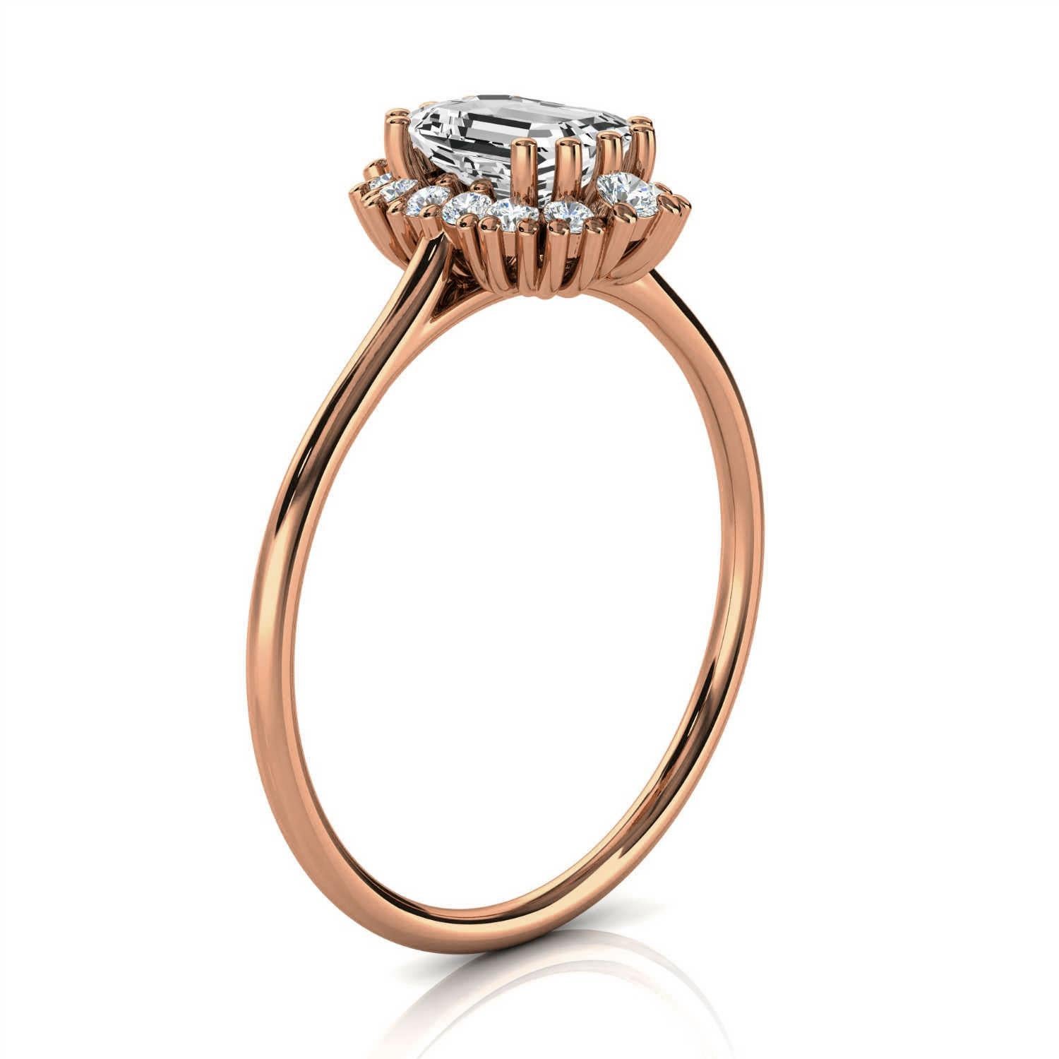 Dieser zierliche, handgefertigte, erdige und organisch gestaltete Ring ist mit einem 1/2-Karat-Diamanten in Smaragdform besetzt. Vierzehn (14) runde Diamanten bilden einen floralen Cluster-Halo auf einem 1,2 mm breiten Schaft und unterstreichen den