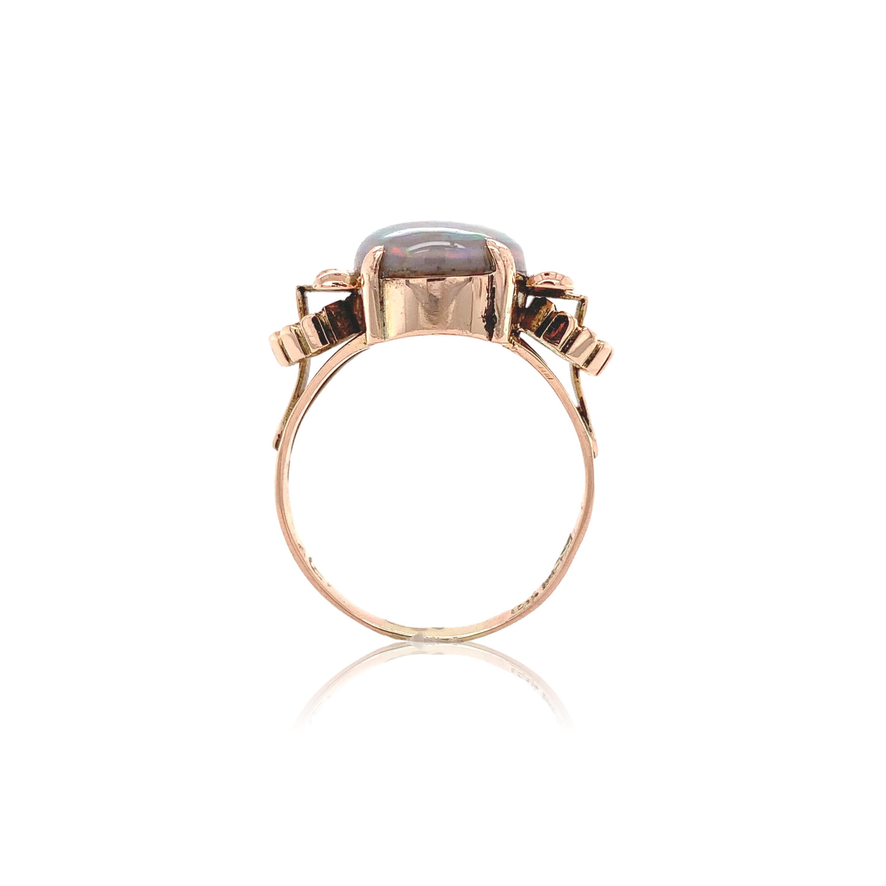Retro 14K rose gold Australian black opal ring. The genuine natural Australian opal measures about 15.3mm x 10mm oval. The opal has a light grey body color (N7) and has primarily pink, blue and green play of color. The ring is hand wrought with