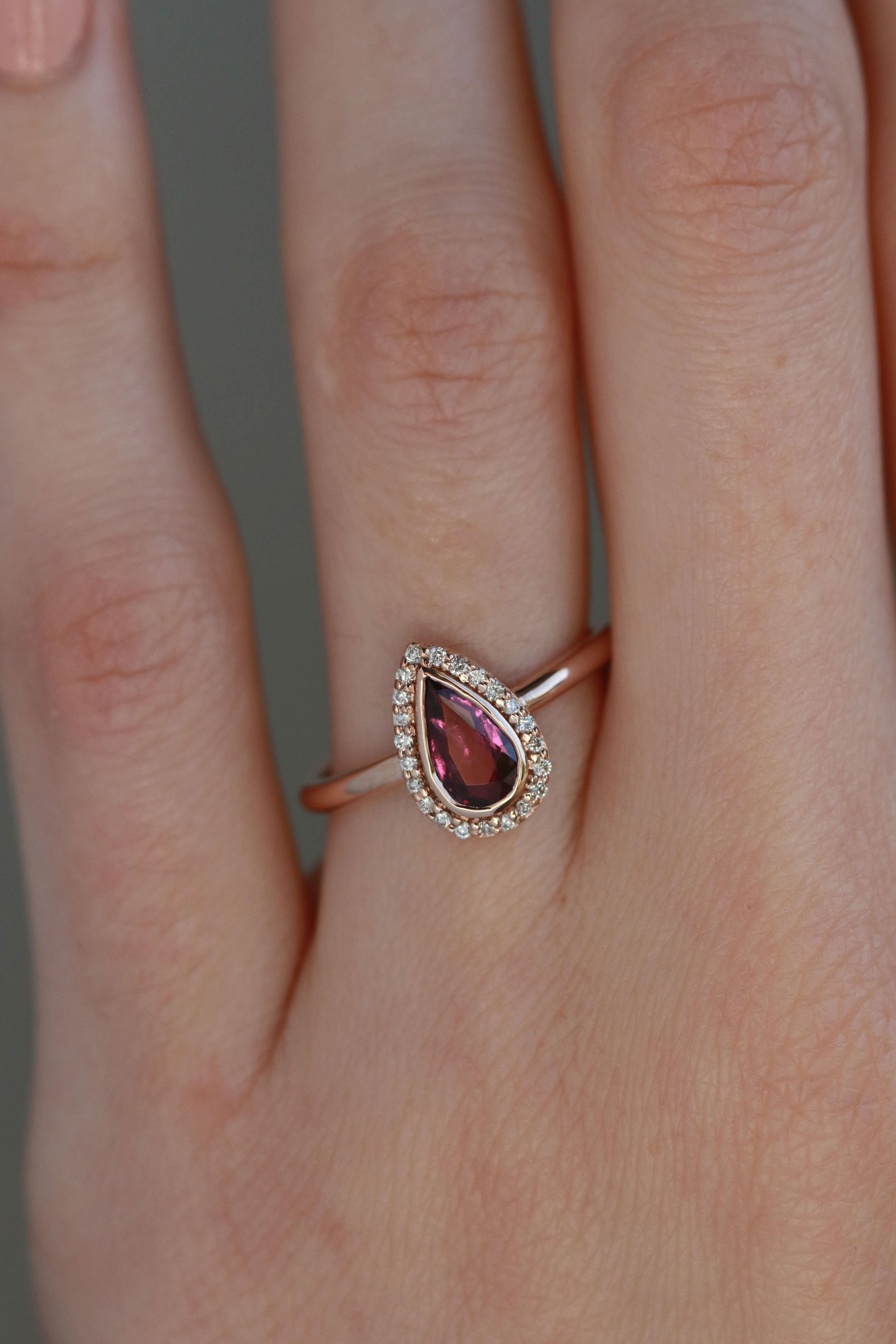 A fancy rosecut pear ruby is surrounded by 22 tiny white diamonds arranged in a halo to mimic the shape of the center stone. Finished in 14k rose gold to enhance the warm tones of the ruby.

Stones:
Ruby Rosecut Pear, 7.9x4.5x2.4mm - 0.7 carats
22