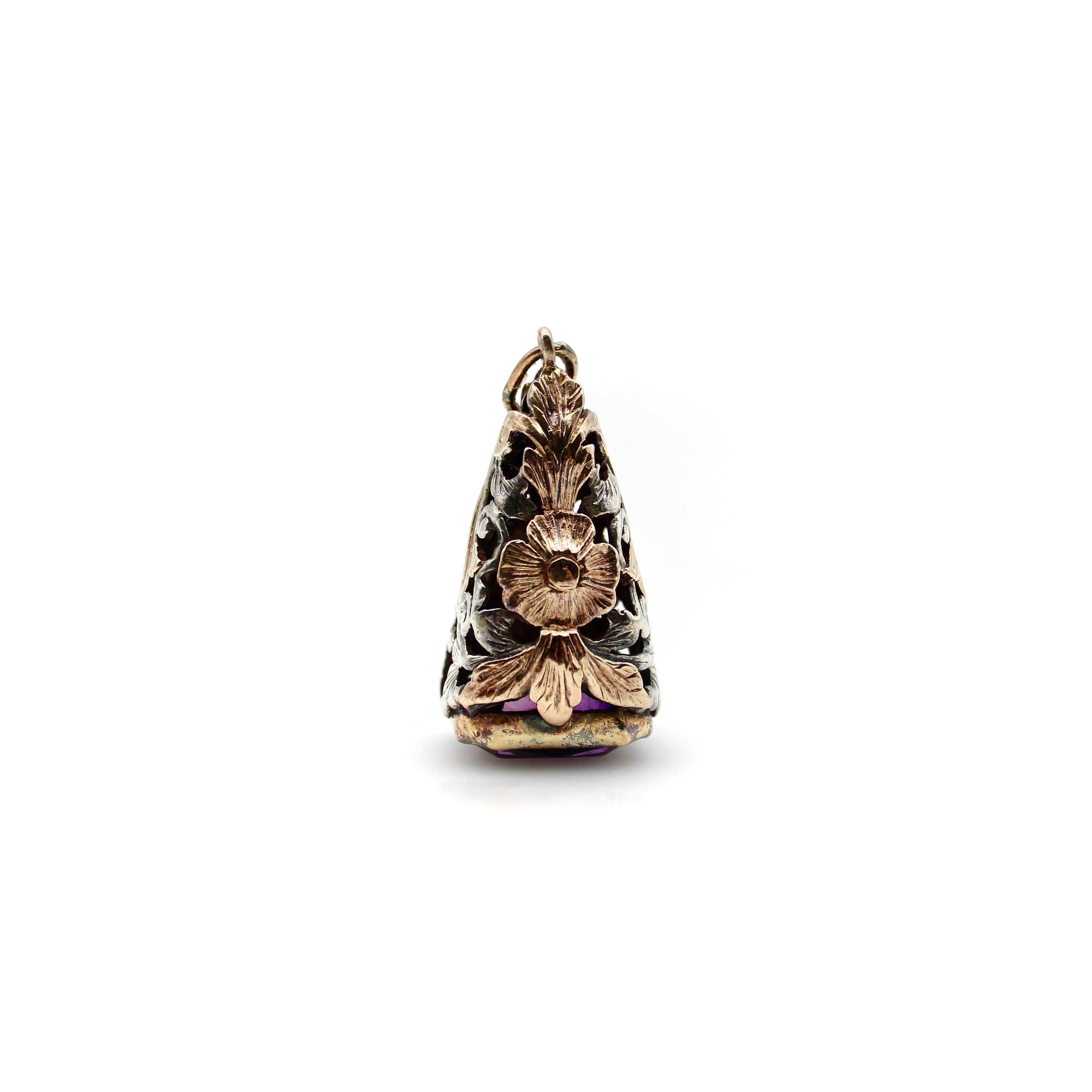 This mixed-metal piece combines 14k rose gold and silver in the beautiful floral and foliate motif of an open work cone. A rose gold flower dangles in silhouette, surrounded by a frame of silver leaves. At the bottom is a deep purple amethyst,