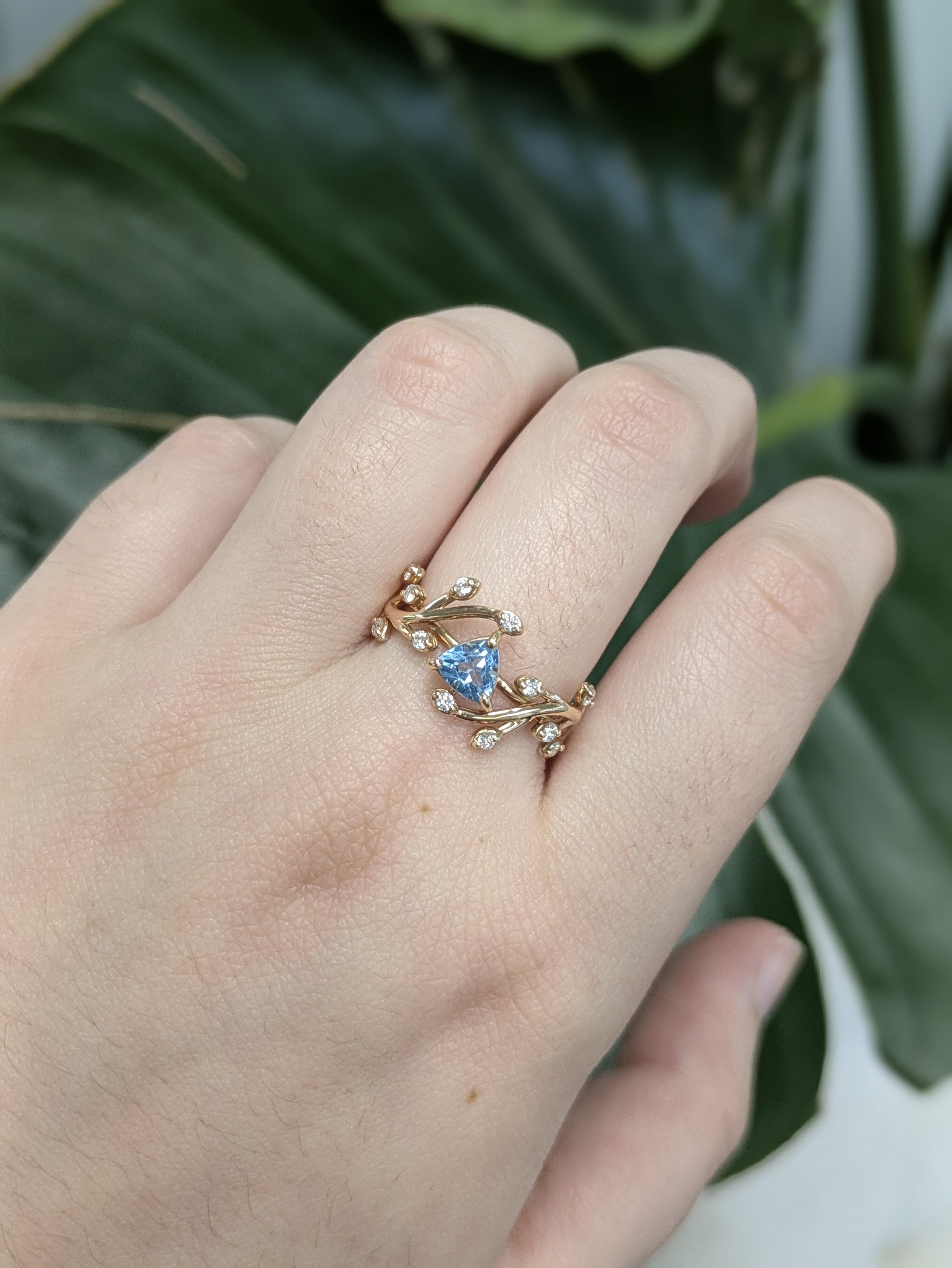 Questo elegante anello mette in mostra un vivido Topazio Blu Svizzero da 0,65 carati con taglio a trilione proveniente dal Brasile, incastonato in 2,33 grammi di oro 14k. Intorno alla pietra centrale ci sono 12 diamanti scintillanti, con taglio a