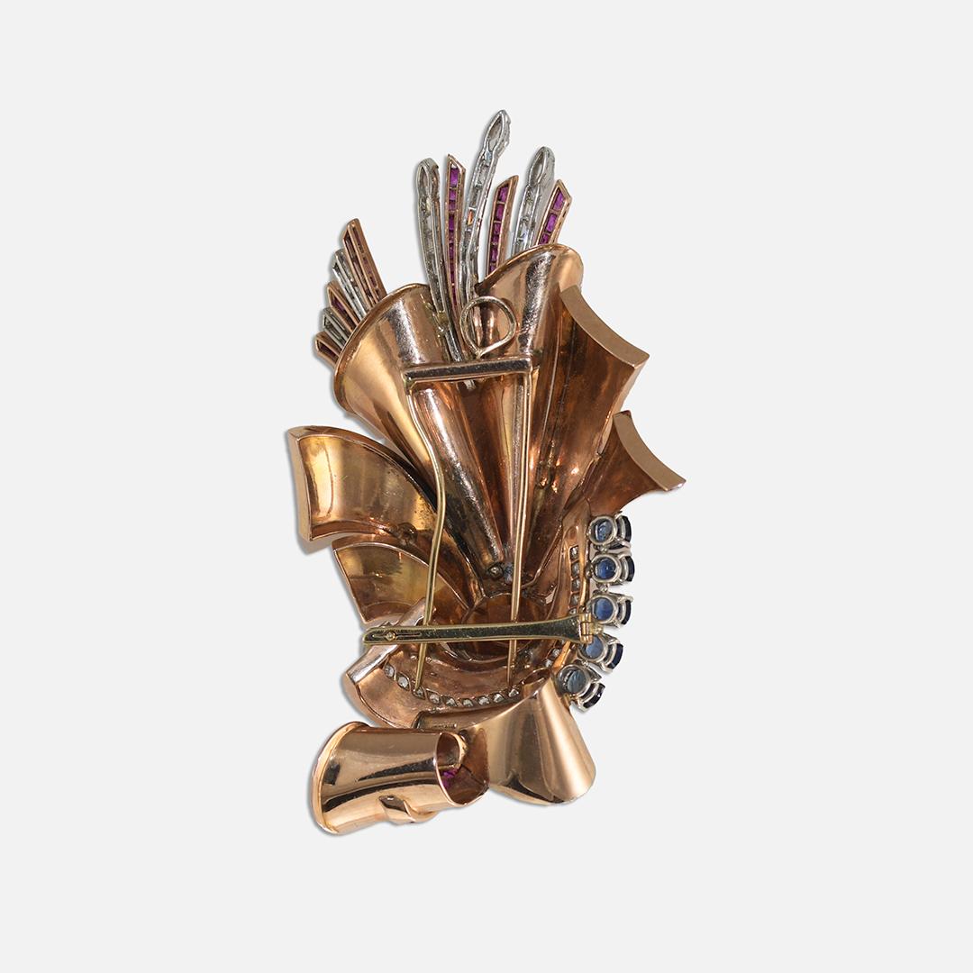 14k rose gold brooch with diamonds, sapphires, and rubies.
The brooch tests 59.5% gold and weighs 78.5 grams gross weight.
There are 5.00 total carats of old-cut round diamonds, H, iI and J color range, mostly Vs clarity.
There are five blue