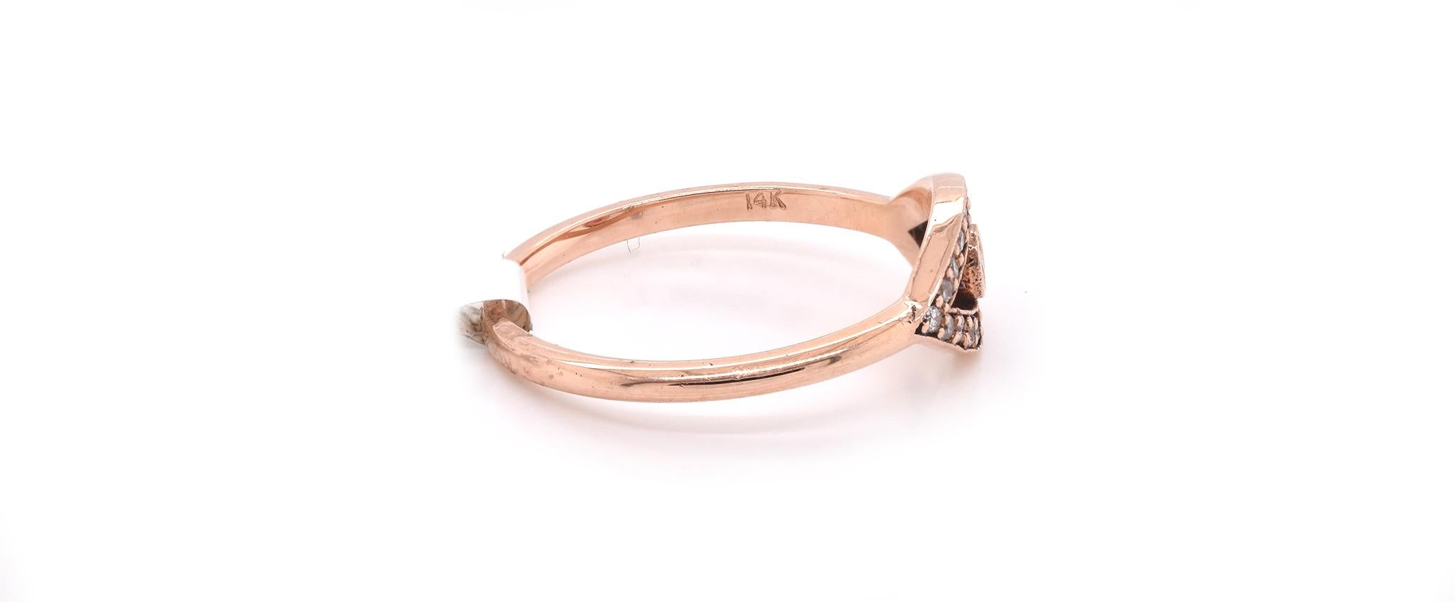 Designer: Custom Design
Material: 14k rose gold
Center Stone: 1 round cut ruby 
Diamonds: 20 round brilliant cuts = 0.13cttw 
Ring size: 6 ½ (please allow two additional shipping days for sizing requests)
Dimensions: ring top measures 6.95mm x 13mm