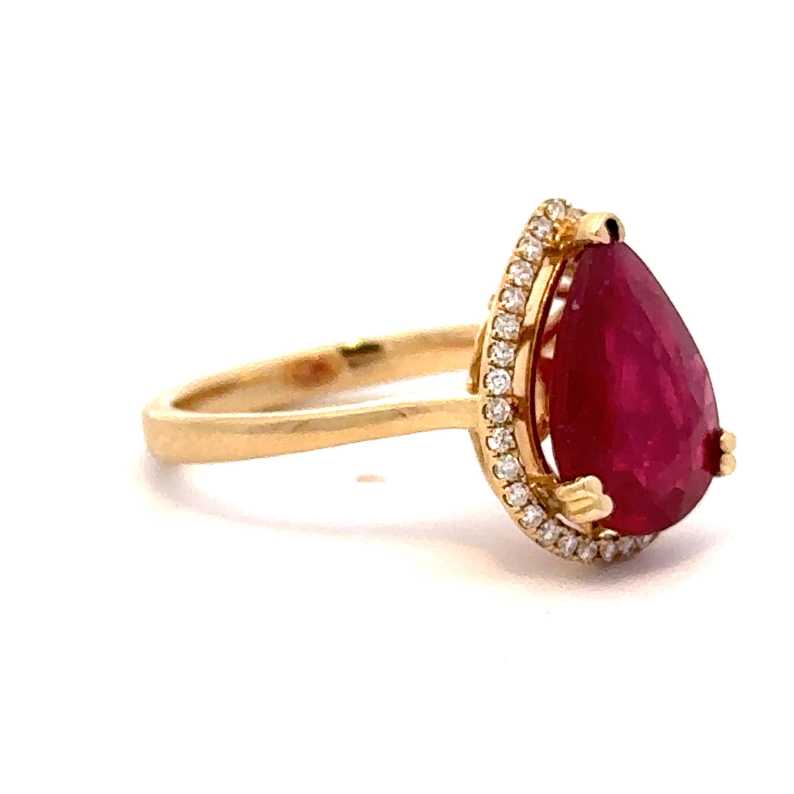 A lovely 14k yellow gold ring presenting a beautiful pear shaped ruby from the mines of Mozambique set within a halo of diamonds. The stone weighs approximately 2.75 carats and is glass fracture filled. The ring is a size 6.5, but can easily be