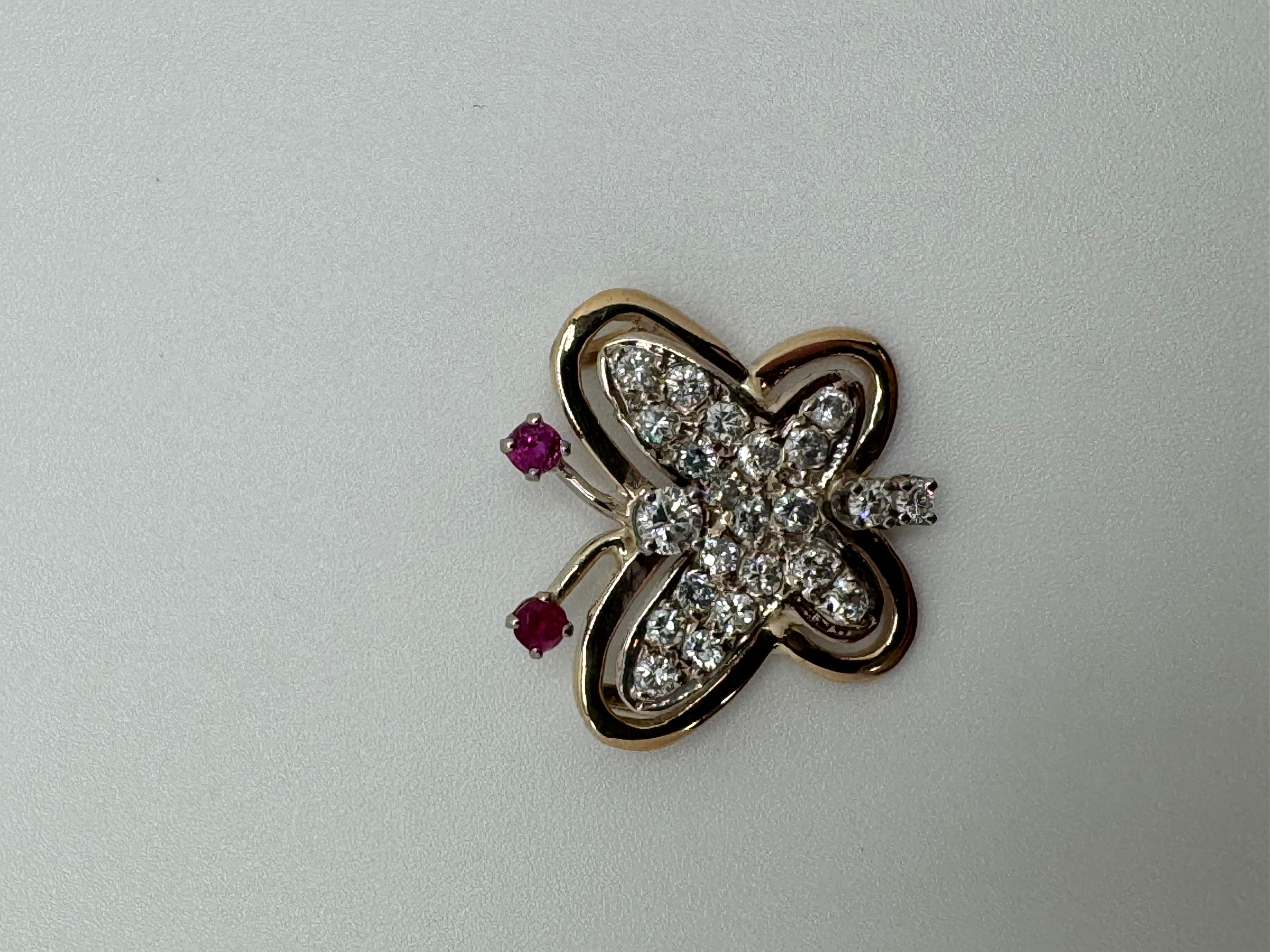 Questo elegante ciondolo a farfalla bicolore è realizzato in oro bianco 14 carati e ornato da gemme vibranti. Gli occhi della farfalla sono caratterizzati da due rubini rosa medi, che aggiungono un accento morbido e suggestivo al design. 23 diamanti