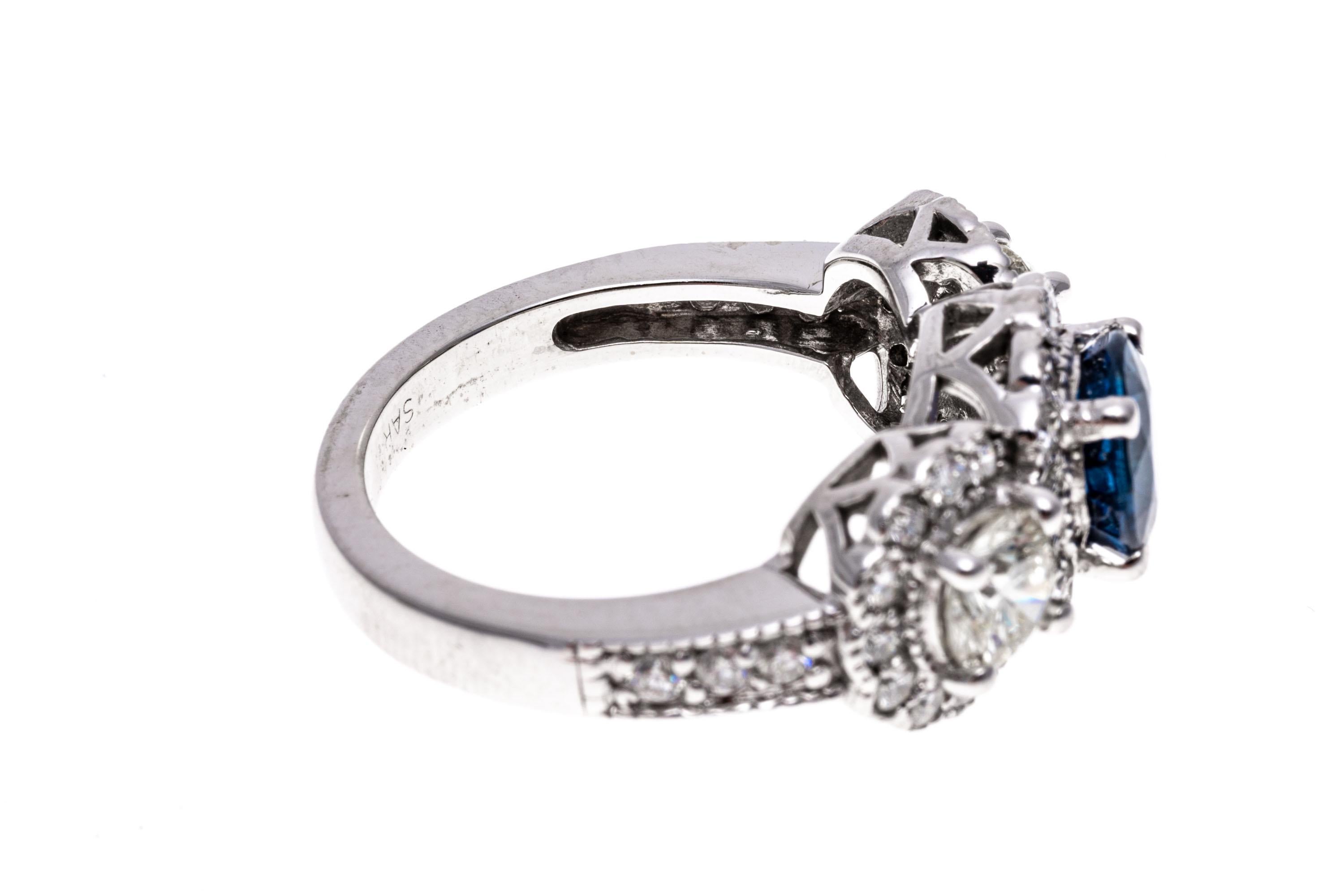 Contemporary 14k White Gold Blue Sapphire and Diamond Halo Three Stone Ring, App. 0.57 TCW For Sale