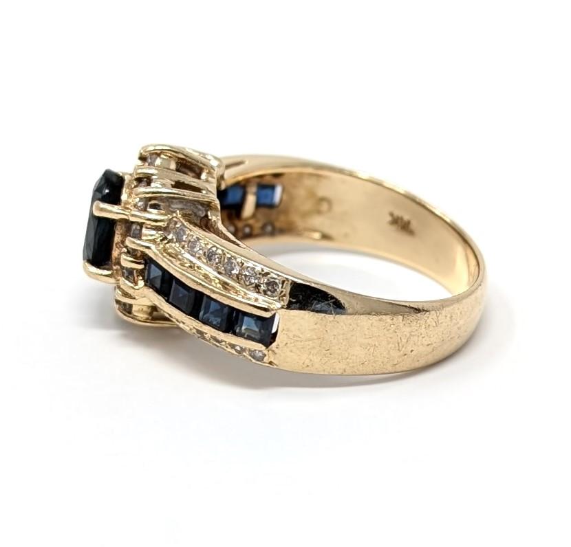 Fabuleuse bague en saphir et diamant 14k présentant un design en halo avec des saphirs latéraux en serti-canal. Il convient parfaitement à un doigt de taille 6,25 et mesure environ 12 mm à ses points les plus hauts et 4 mm à ses points les plus