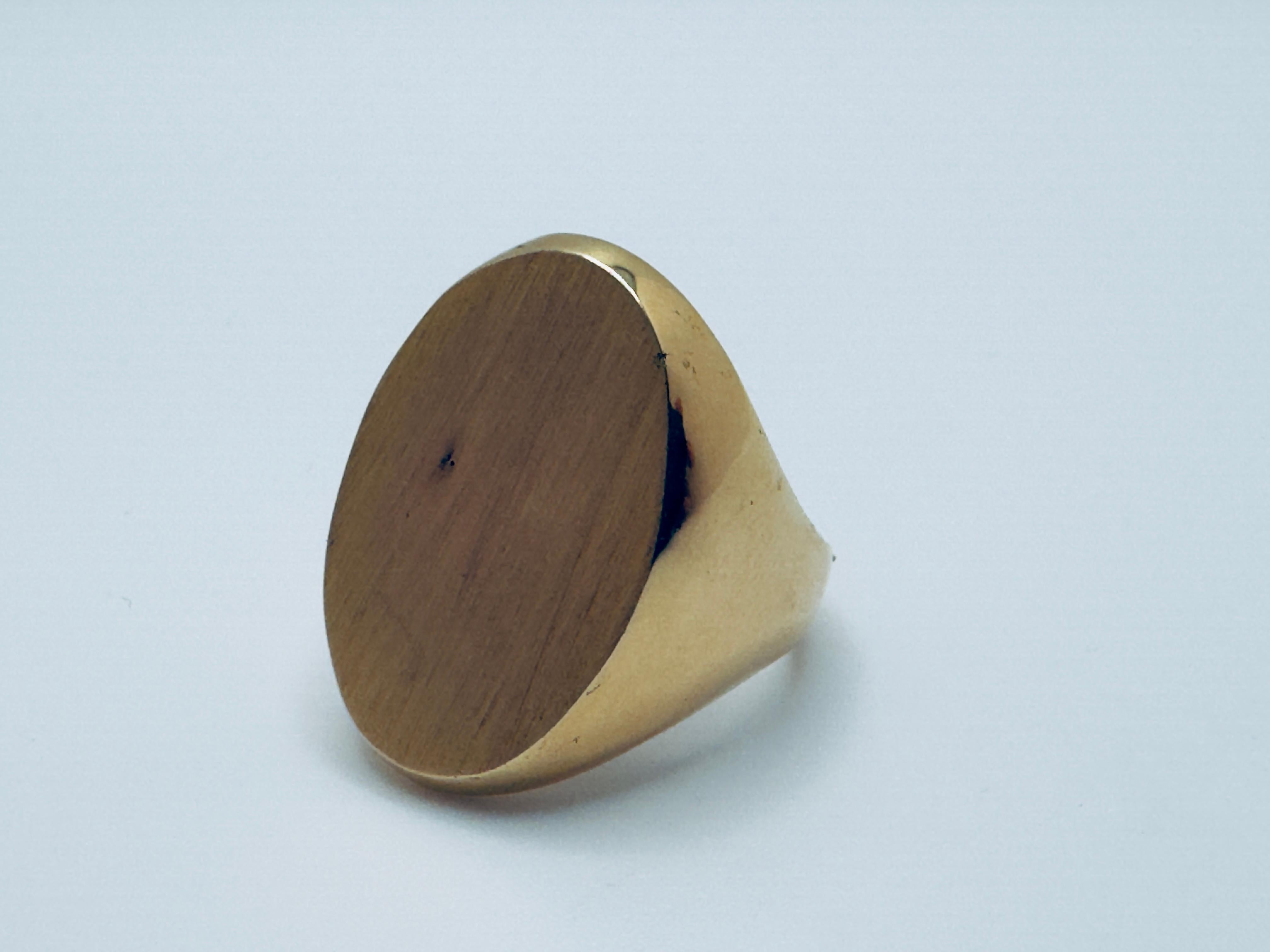 Crafted in solid 14K yellow gold, this bold signet ring features a substantial oval face measuring approximately 25x18mm, offering a sleek canvas ideal for engraving or left blank for a clean, minimalist look. The smooth, high-polished finish