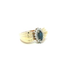 Ring aus 14-karätigem Massivgold mit einem 0,97 Karat schweren Saphir im Marquise-Schliff, umrahmt von Diamanten, mit breitem, ausgestelltem Band