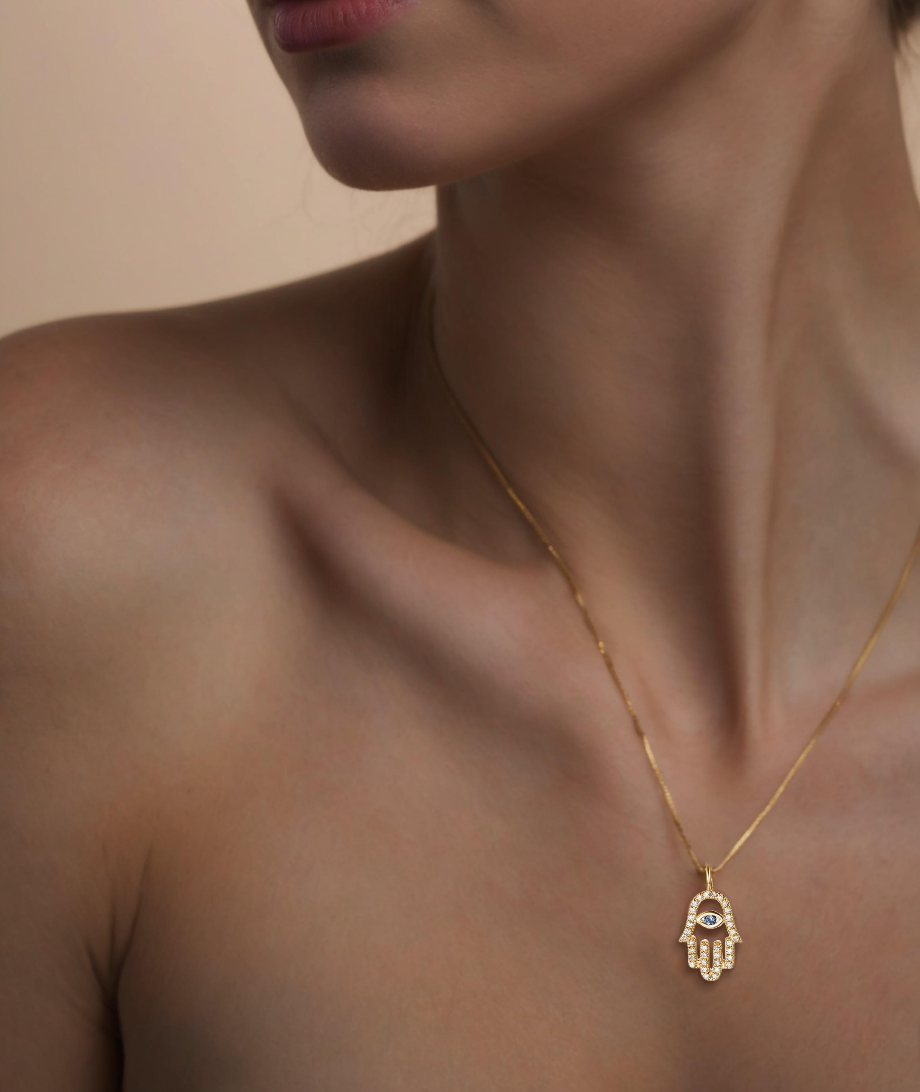 A vibrant sapphire sits at the center, adding a touch of luxury and allure. Suspended on a delicate gold chain, this necklace is both a meaningful talisman and a versatile accessory that complements any outfit. Perfect for layering or wearing solo,