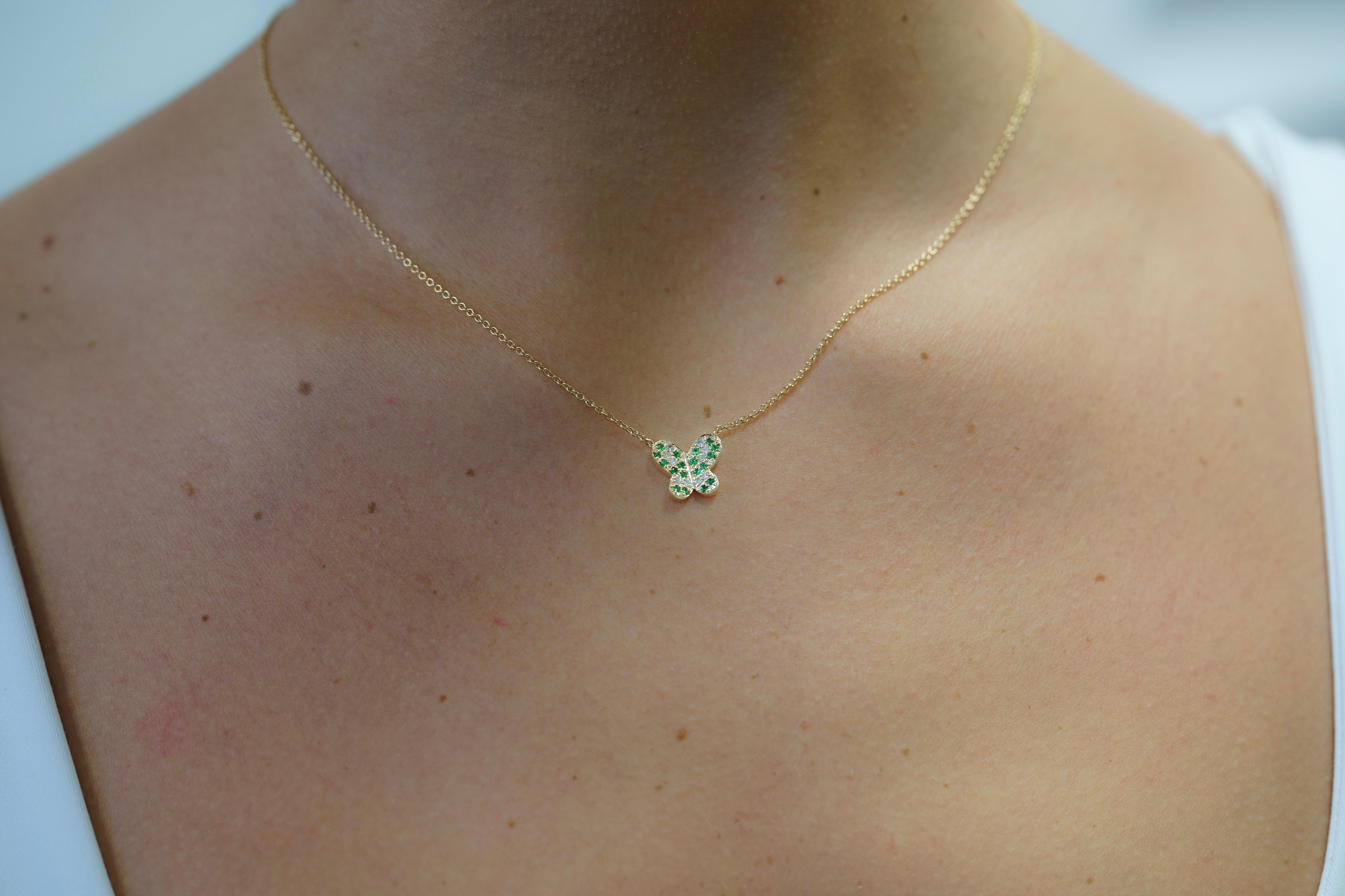 Presenting a Natural Green Tsavorite and Diamond Butterfly Motif Pendant, gracefully made in 14K Solid Yellow Gold.

This necklace features a round-cut natural green tsavorite and round-cut natural diamond pave cluster. Fixed on an 18-inch cable