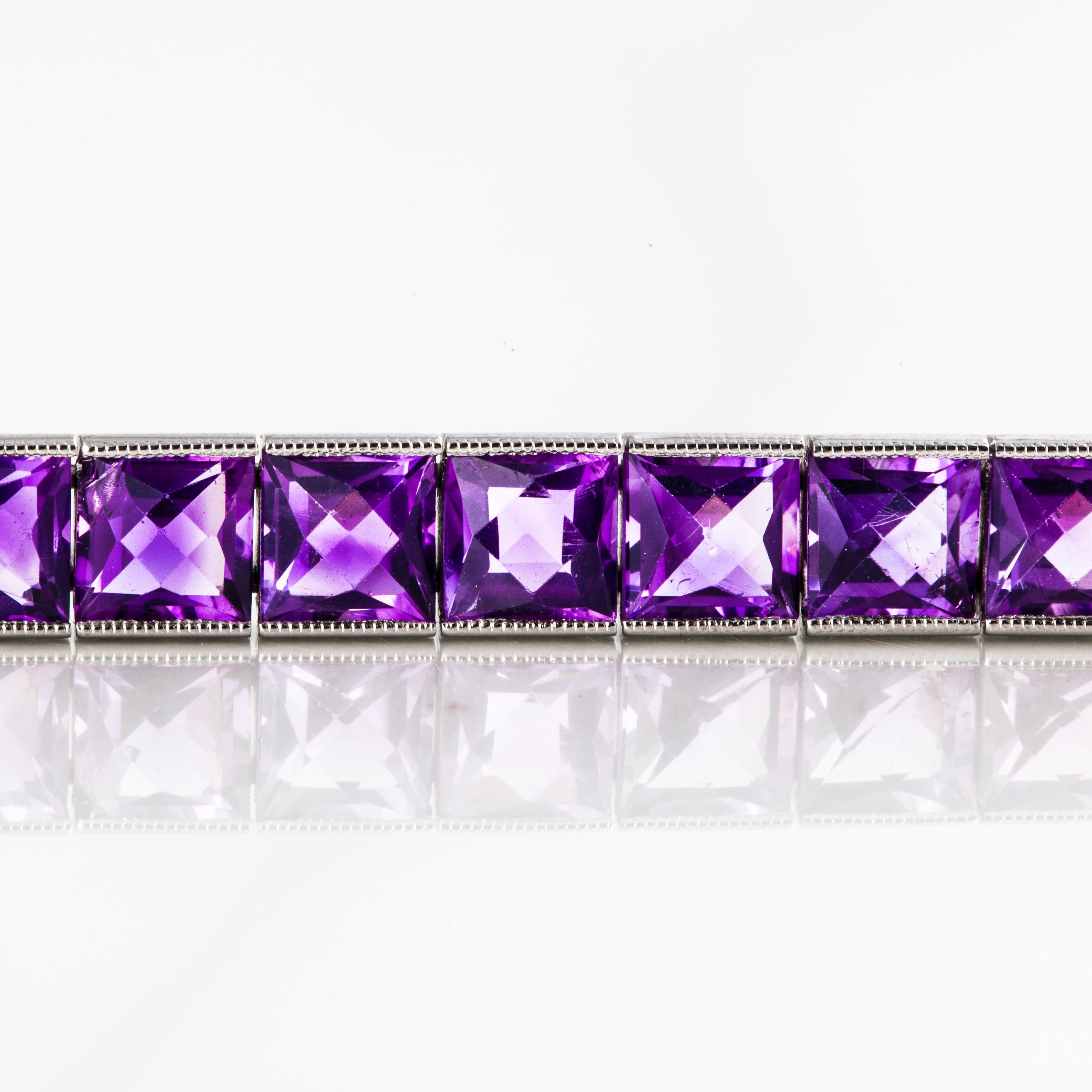 Line bracelet composed of 14K white gold featuring square-cut amethyst stones.  There are 37 faceted amethysts that total 22.20 carats. The bracelet is engraved on both sides with a tongue closure and safety clasp on the underside.  It measures 7