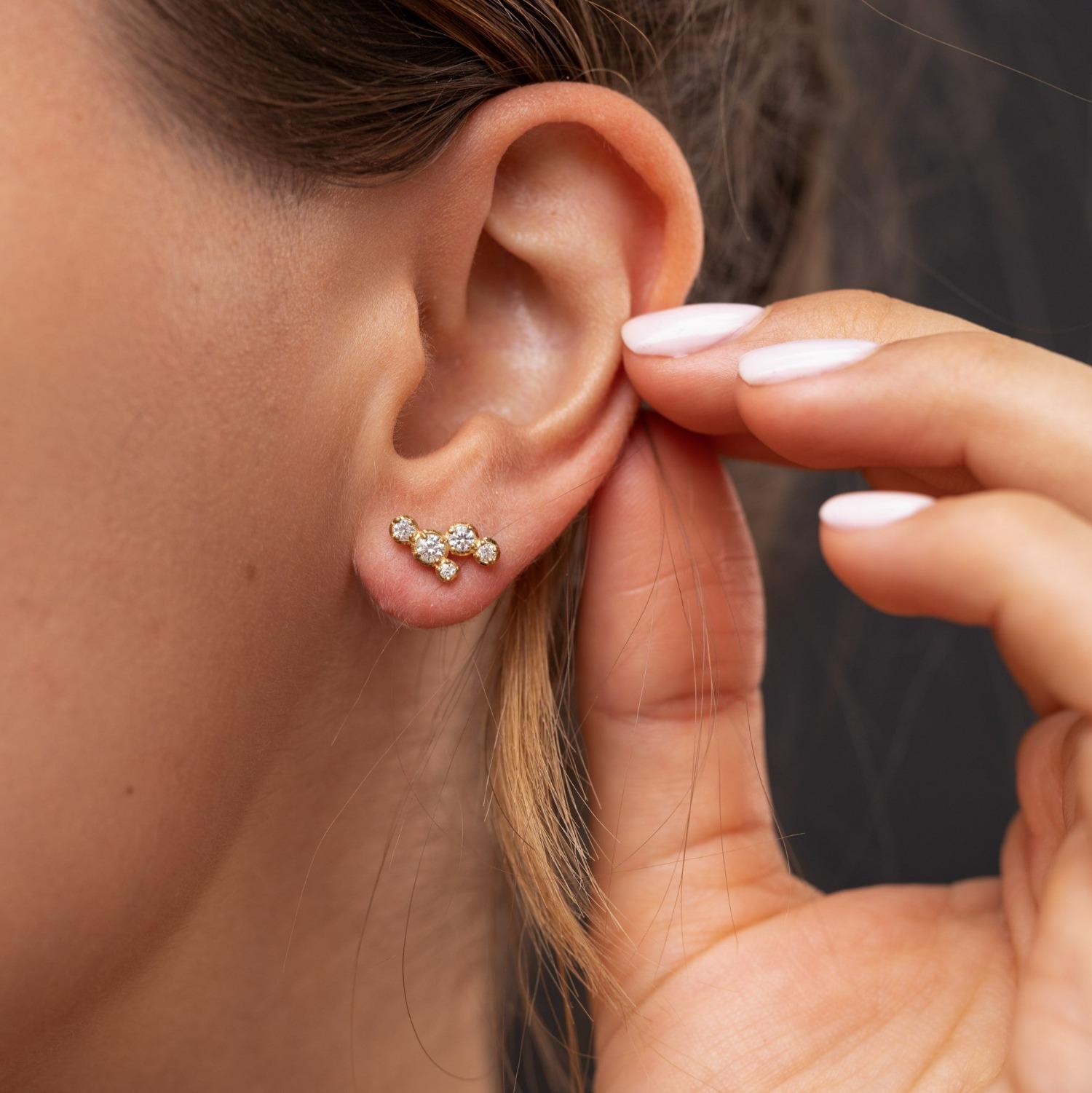 Delicate ear studs with five claw set diamonds in a random celestial pattern. These handmade 14ct yellow gold earrings, with irregular sized stones, evoke an astrological constellation. Made with recycled gold. Stone sizes - 1.5 to 3.0mm with total