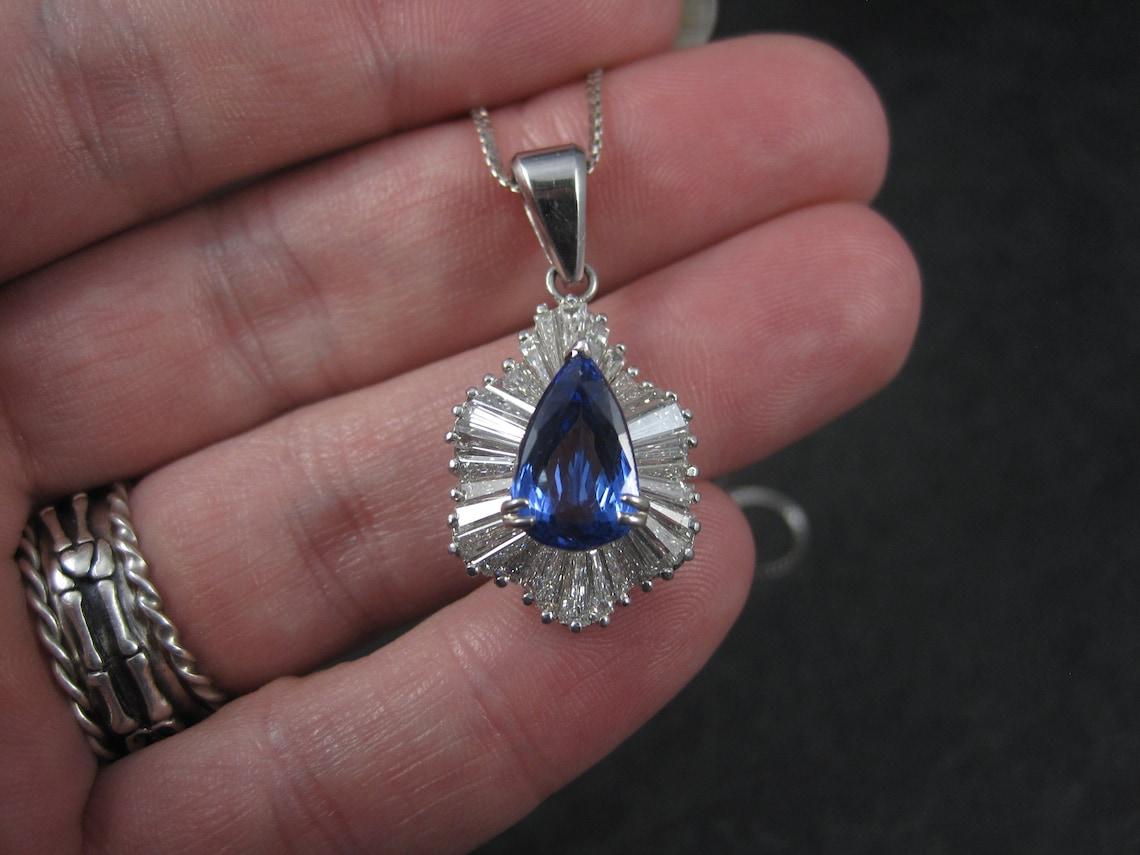 This gorgeous vintage tanzanite and diamond pendant is 14k white gold.

It features a 3.05 carat pear cut tanzanite accented by a halo of baguette cut diamonds.

The tanzanite measures 11.74 x 7.5 x 4.72mm and is rated dark blue violet, SD.

The