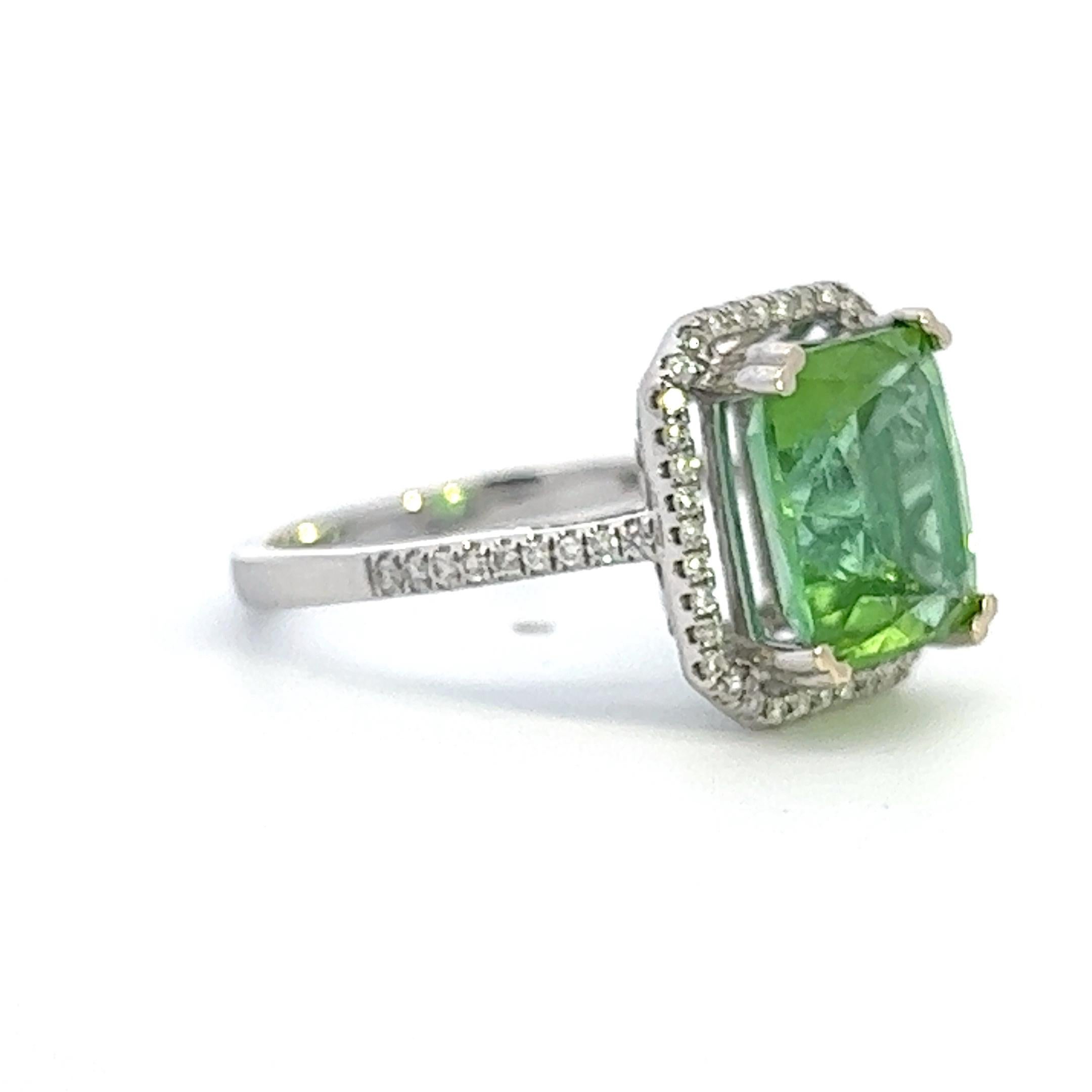 An incredible blue green tourmaline set within a halo of diamonds in a 14k white gold ring. The green tourmaline has a remarkable blue hue and weighs approximately 4 carats (measured in setting). The ring is a size 6.5 but can easily be resized. 
