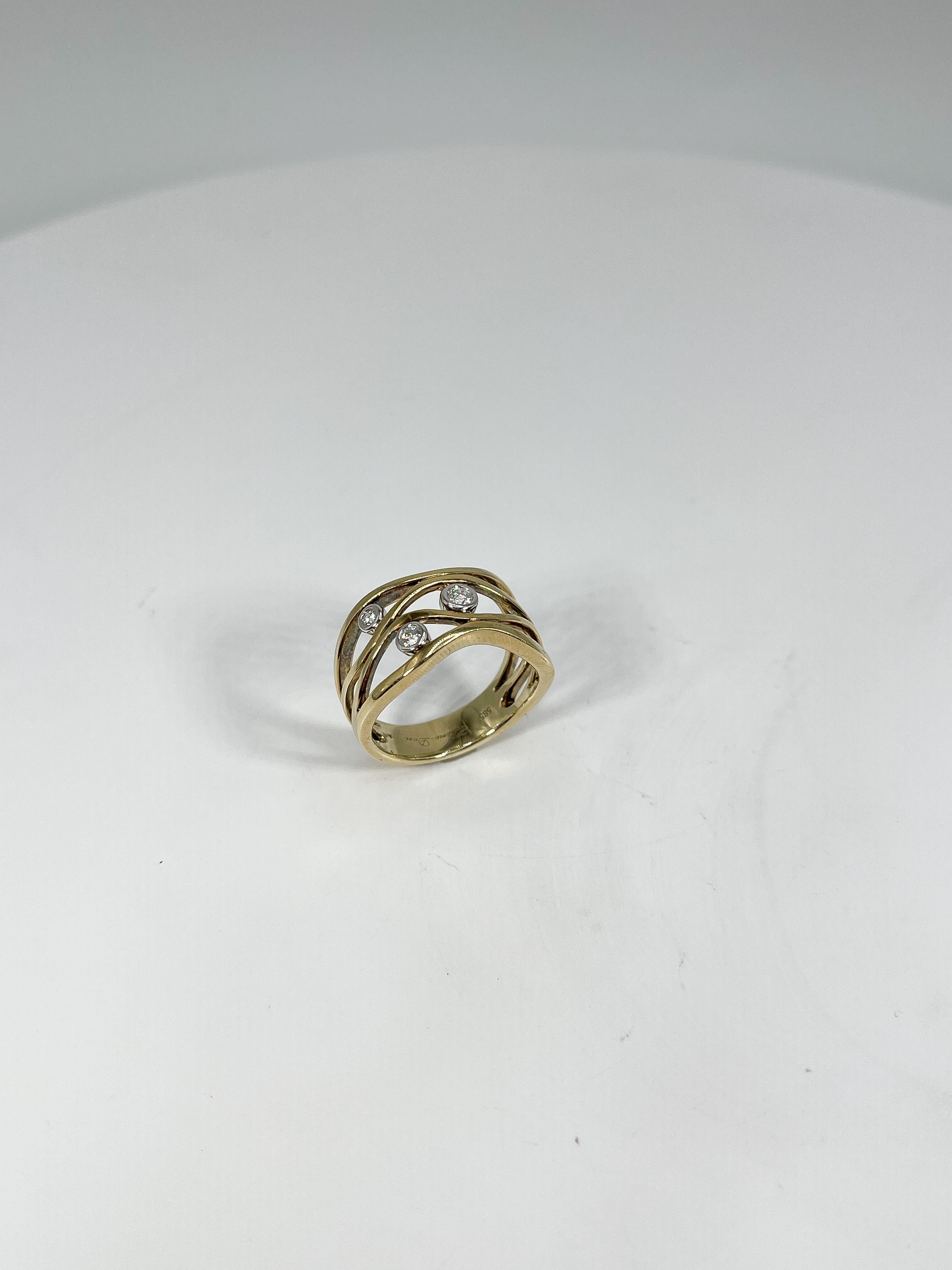 14k two toned .13 CTW diamond ring. The ring has a yellow gold wavy design with 3 round diamonds in a white gold bezel setting. The width of the ring is 10.8 mm, has a weight of 5.64 grams, and the size of the ring is a 6 1/2. 