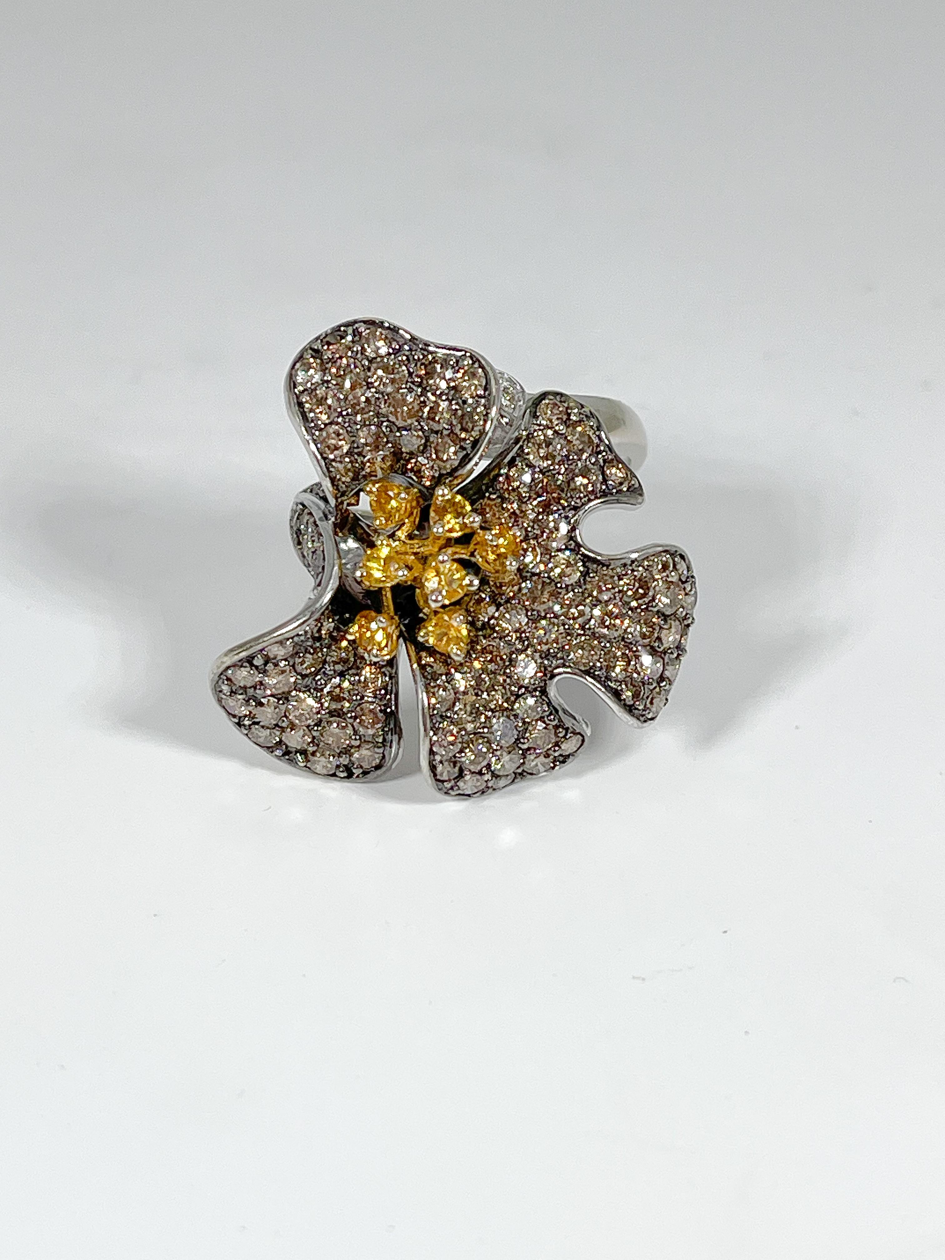 14k two toned flower ring with chocolate diamonds as the petals, yellow diamonds in the center, and accenting white diamonds on the leaf. Ring is a size 8 3/4, measures 28.6x26.9 mm, and weighs 10.28 grams. 