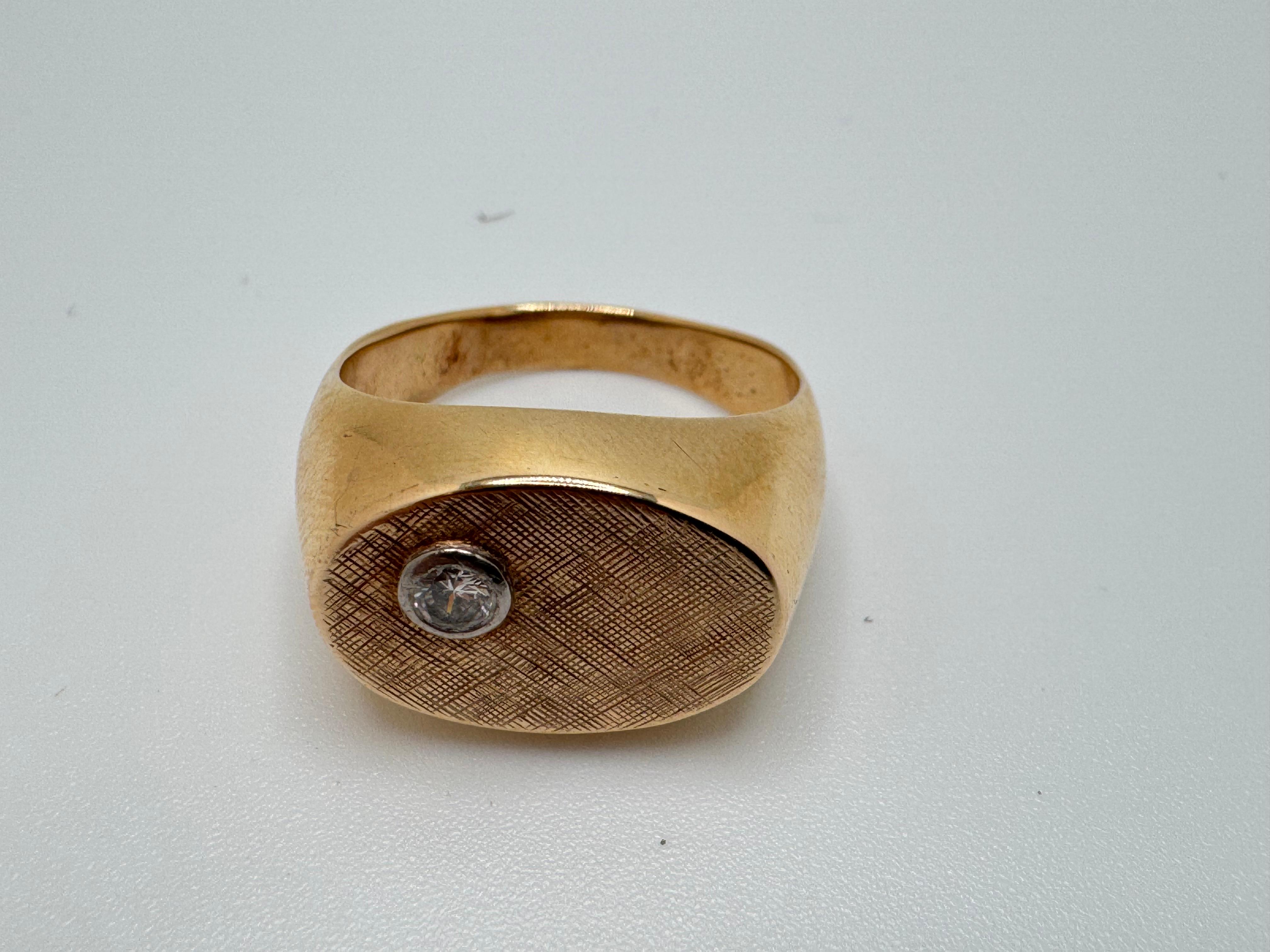 Elaborado en oro amarillo de 14 quilates, este anillo para hombre presenta un diseño atemporal y refinado. En su centro hay un único diamante redondo, engastado en bisel en una placa de forma ovalada para un engaste elegante y seguro. El diamante