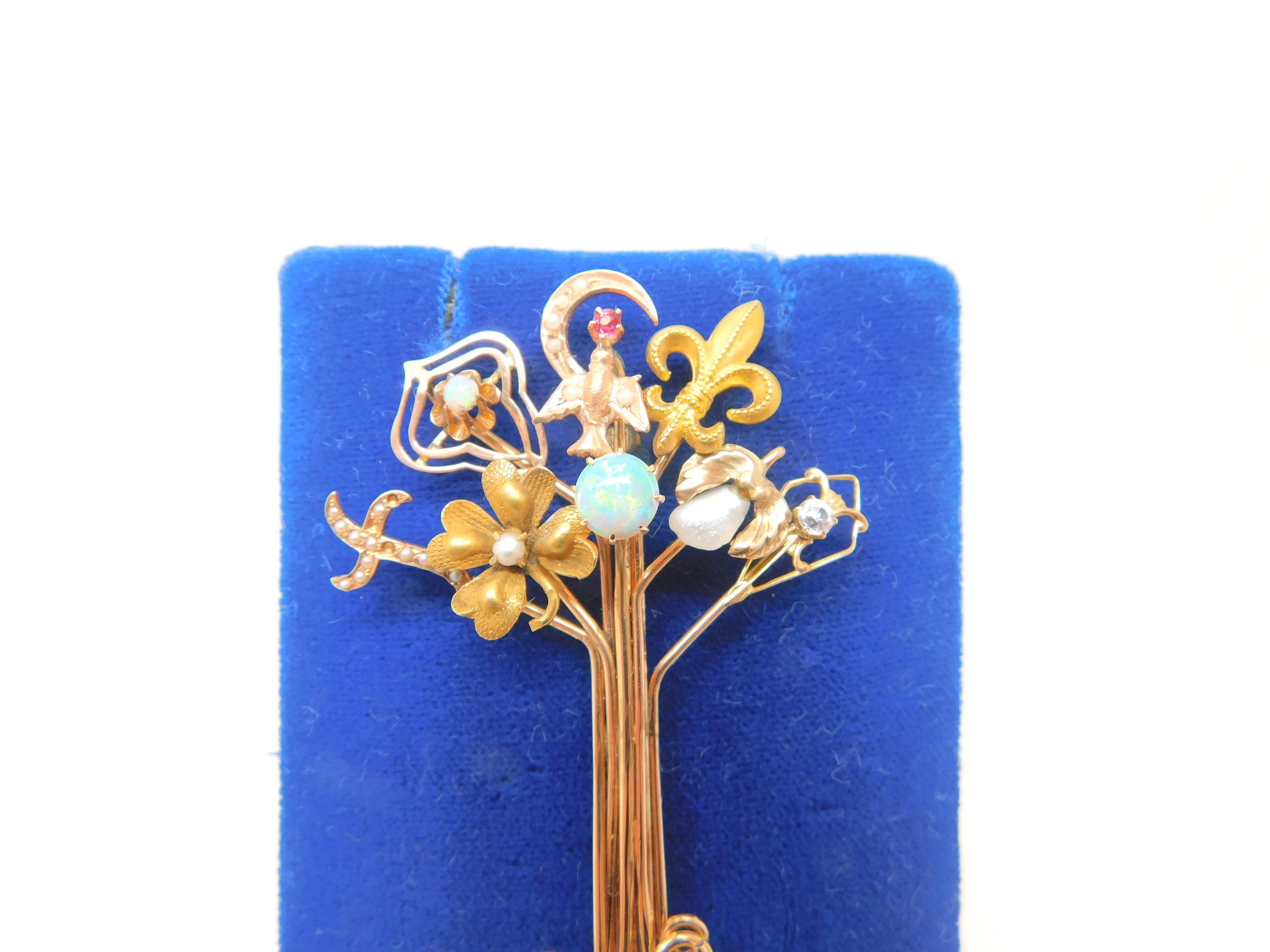 Victorian rose gold stick pin collection pin in the form of a tree.  The pin is made from 8 stick pins that are 10K and 14K.  The pins including: an opal, fleur de lis, freshwater pearl, a dove with a ruby, a cross with seed pearls, a 4 leaf clover
