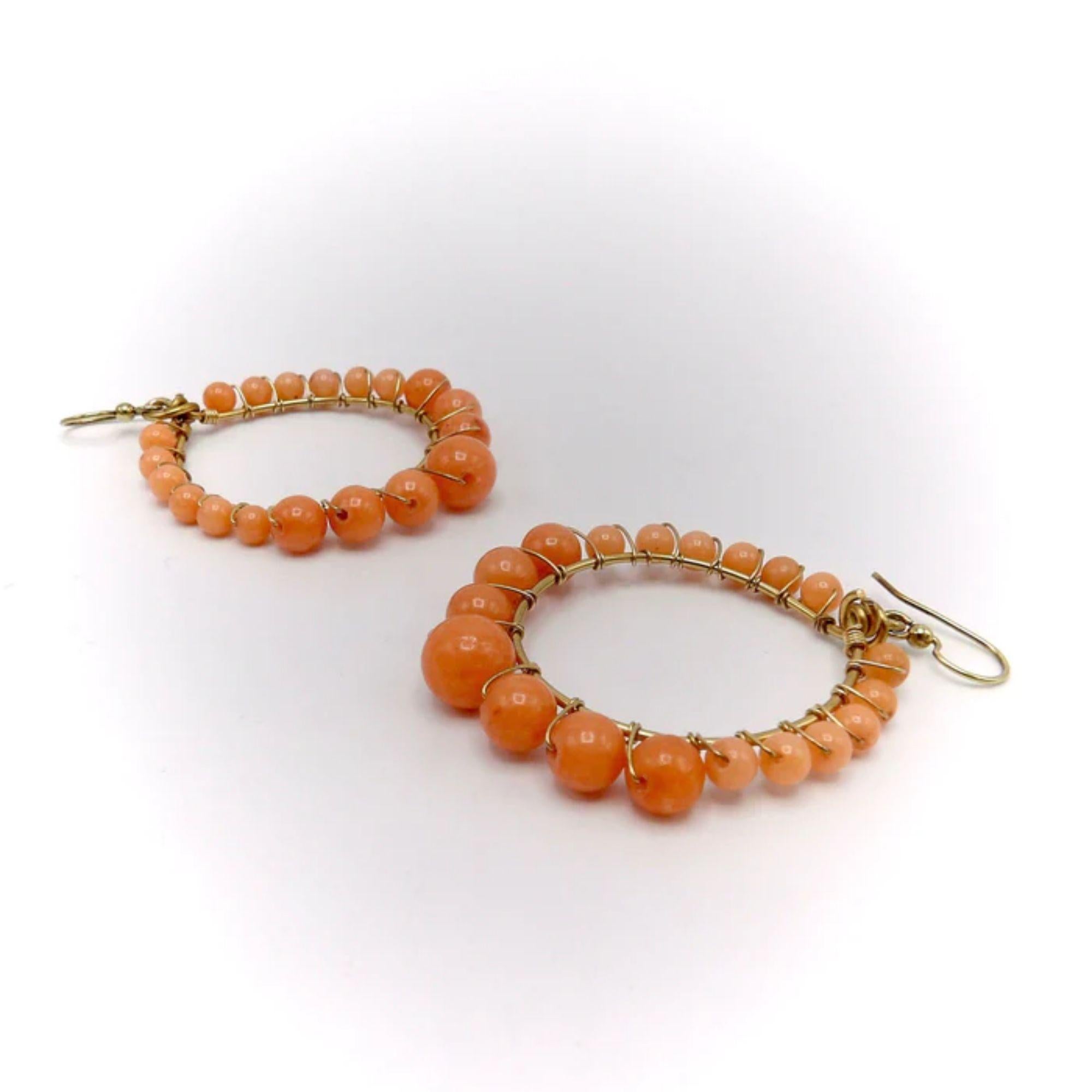 These coral-colored vintage hoop earrings are perfect for the summer! They feature glass beads delicately attached to a 14k gold hoop. The beads closely resemble coral and create a bold yet light hoop variation. 
 
The beads increase in size from to