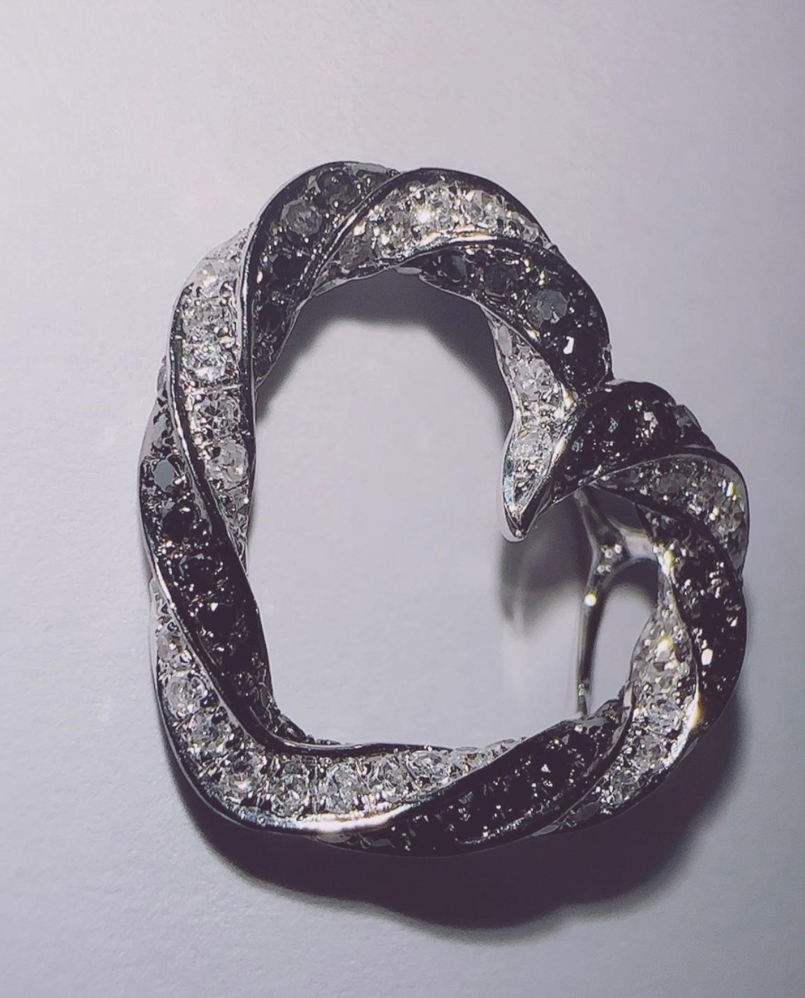 Il ciondolo a forma di cuore con diamanti neri e diamanti bianchi in oro bianco 14 carati è posizionato sul collo. 
 