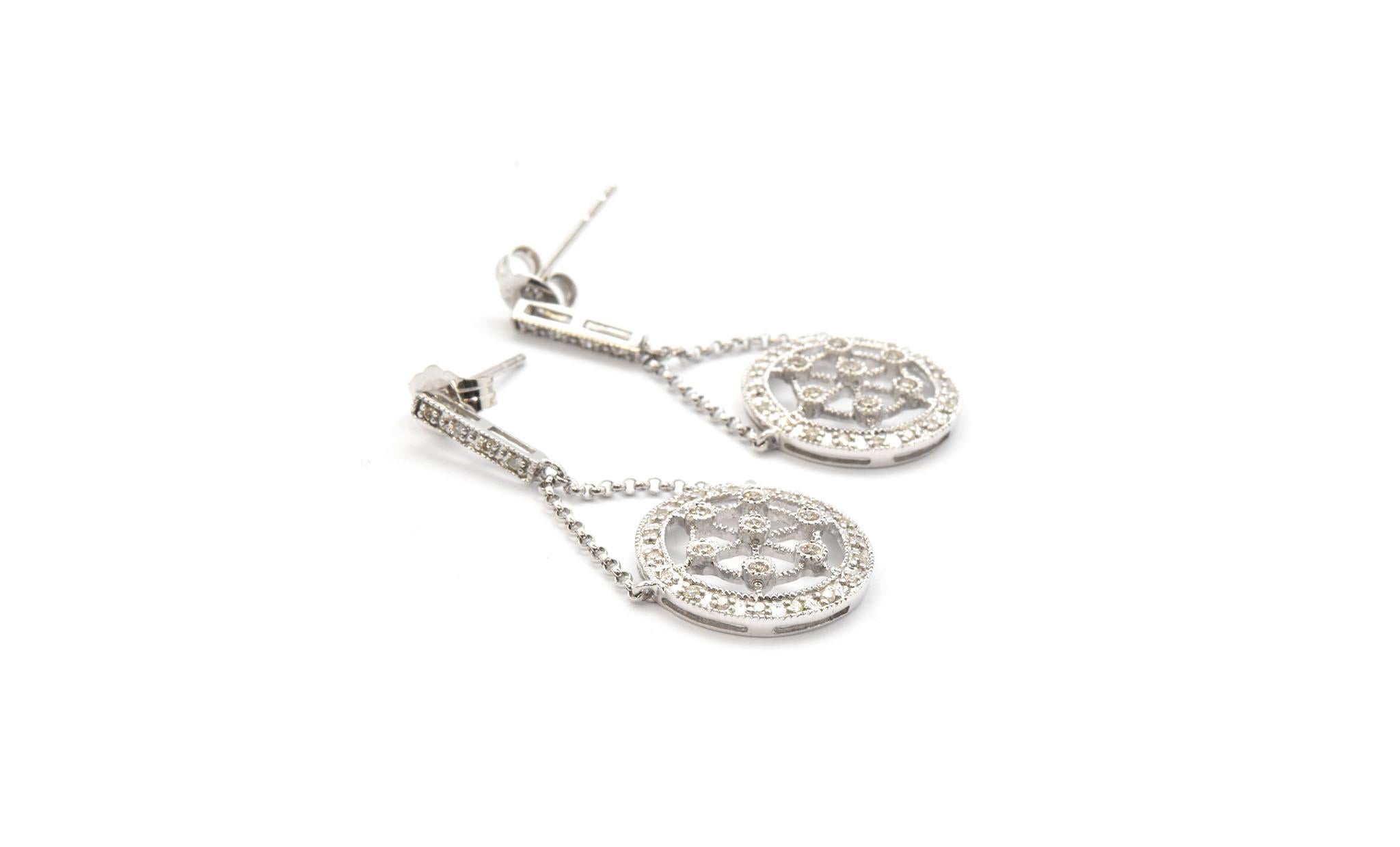 This pair of dangling earrings are fashioned from 14k white gold and set with 60 round diamonds! The circles dangle from the white gold straight diamond line on circle links, the dangle is 12.66mm. Attached to the circle links is an 14k white gold