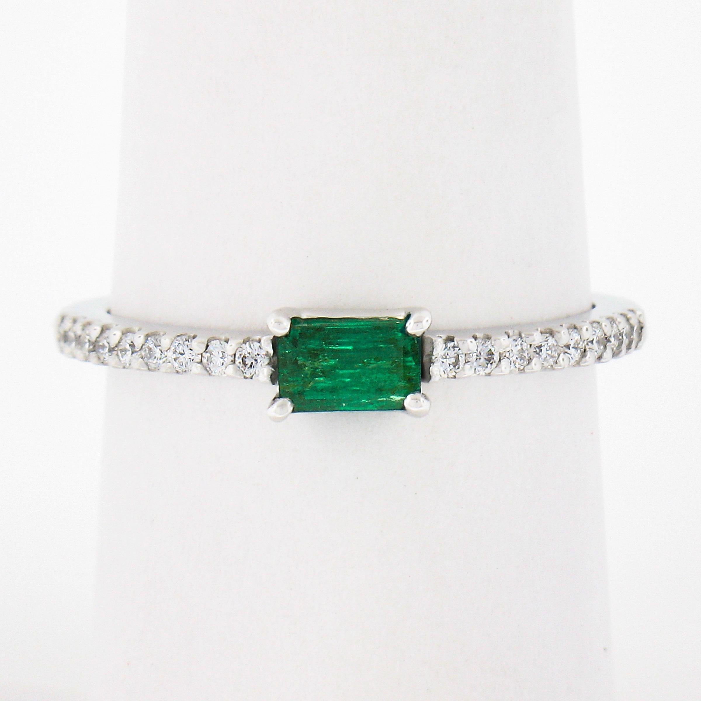 A simple yet gorgeous, emerald solitaire ring that is newly crafted from solid 14k white gold. The solitaire is elongated rectangular step cut with a nice and rich green color accented with 18 diamonds that are all set in prongs settings. This