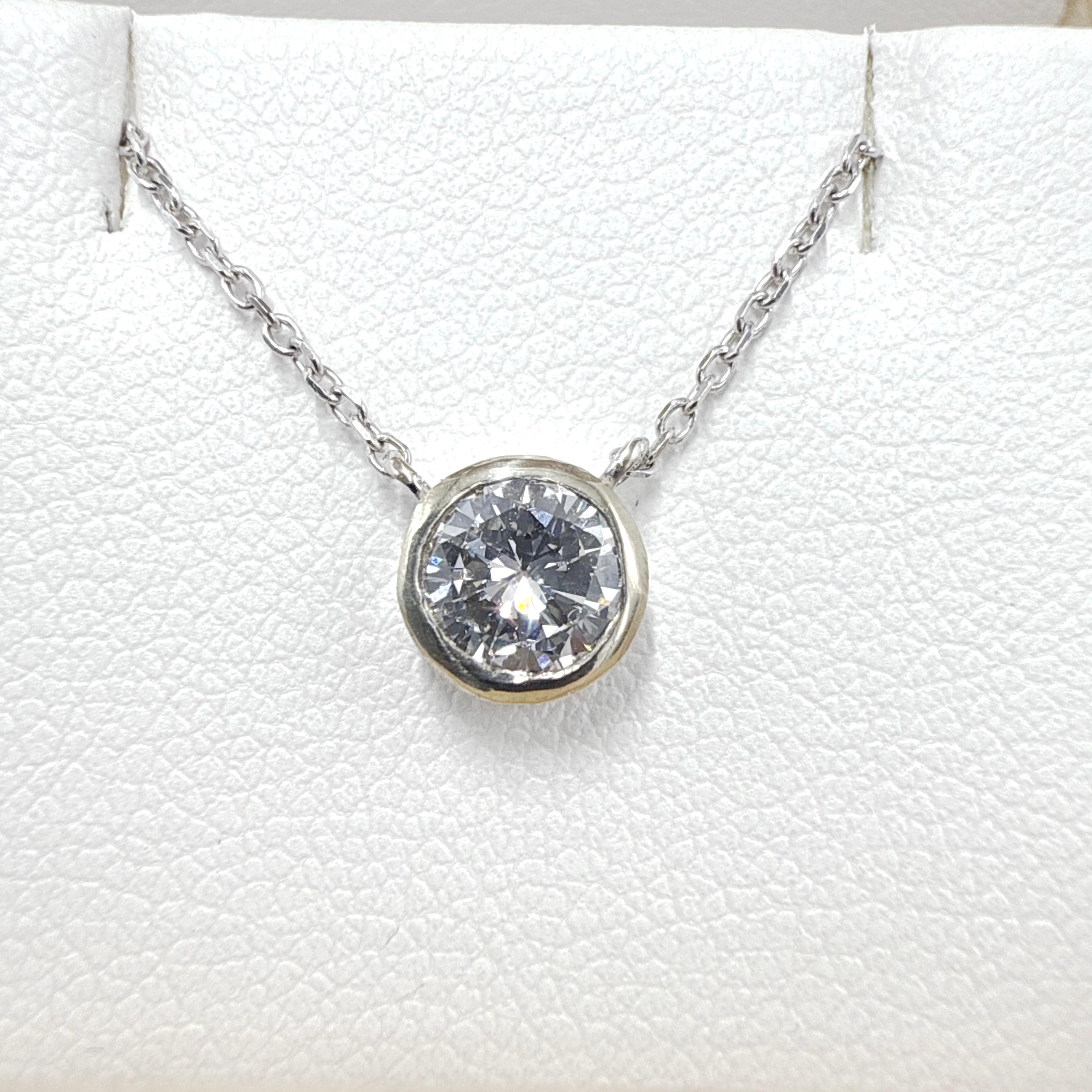 This brand new necklace features a 14K white gold Rolo link chain paired with a round bezel-set diamond solitaire pendant. The chain measures 18.00 inches in total length and has an average width of 0.60 mm. It is machine-made with hand-finished