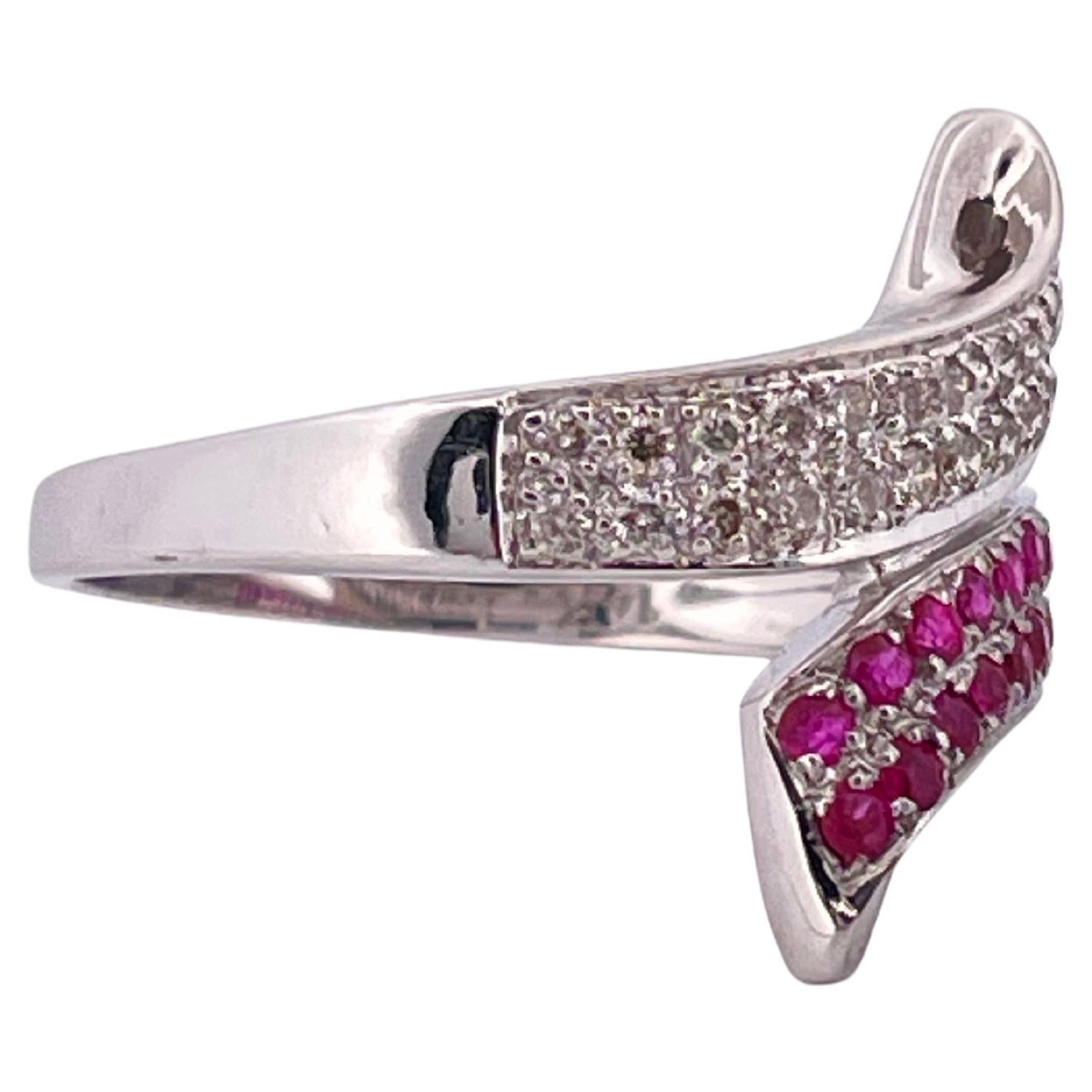 Este elegante anillo de derivación, elaborado en oro blanco de 14 quilates y con un peso de 3,6 gramos, muestra una sorprendente interacción de diamantes y zafiros rosas. Un brazo del diseño en bypass está engastado con aproximadamente 0,50 quilates