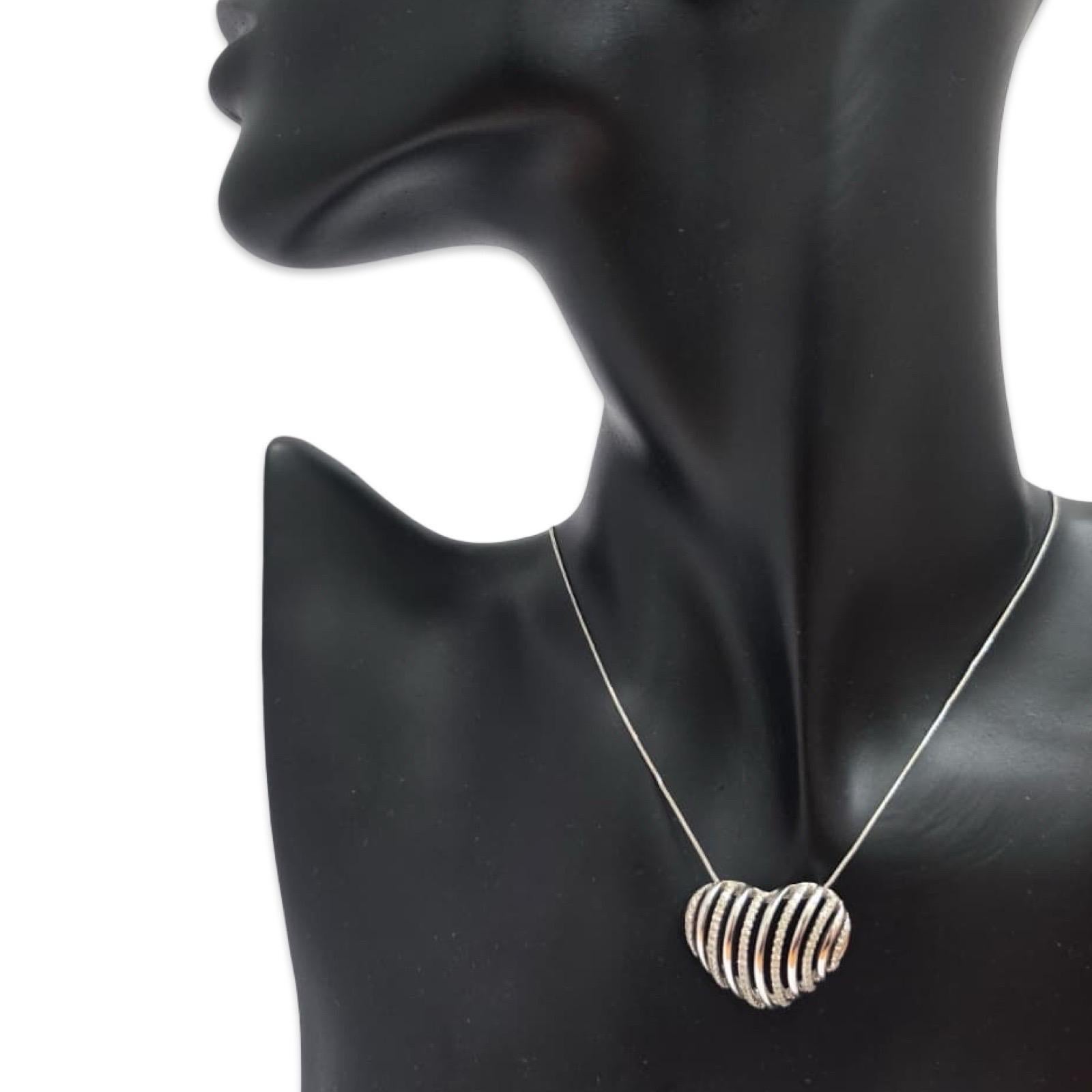 Un pendentif en forme de cœur en ruban de diamants, frappant et sculptural, réalisé en or blanc massif 14K et suspendu à une élégante chaîne italienne en or blanc 14K. La forme dramatique et dimensionnelle du cœur présente des courbes fluides en