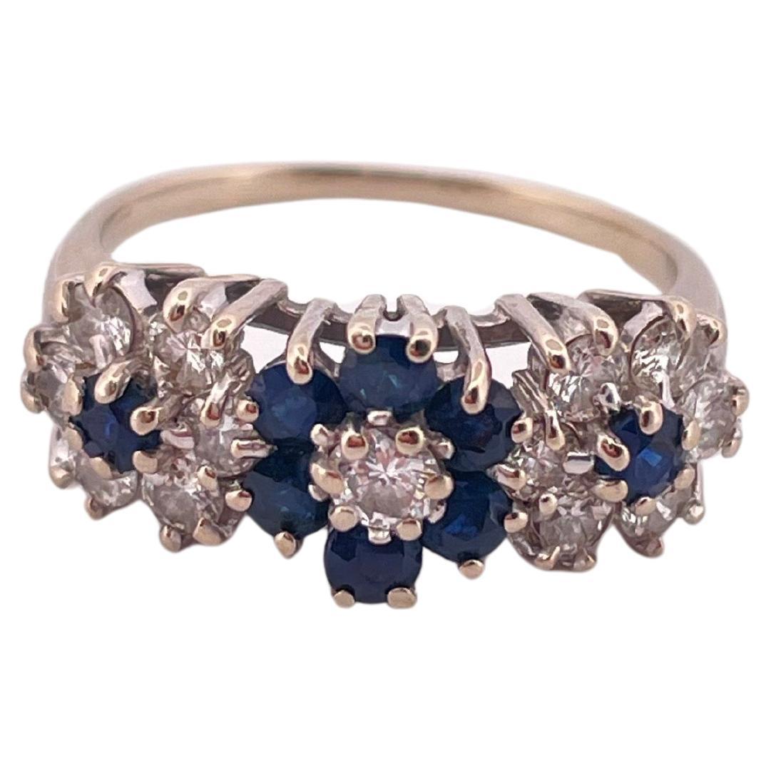 Questo elegante anello in oro bianco 14k sfoggia un intramontabile design a grappolo floreale, con 0,87 carati di diamanti e 0,50 carati di zaffiri blu intenso. Tre distinti gruppi ispirati a un fiore abbelliscono la parte anteriore del cinturino,