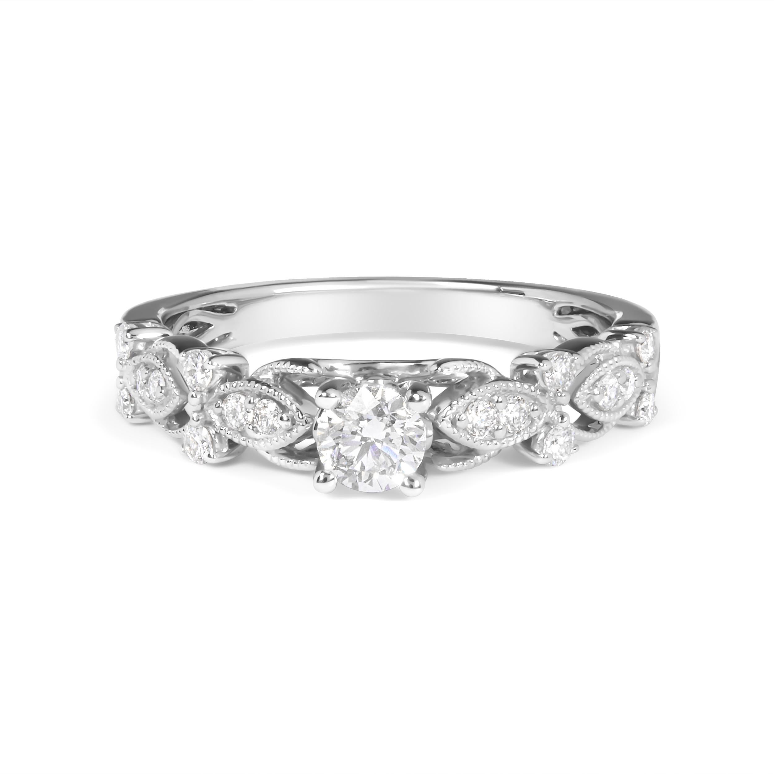 Enveloppez l'être cher d'un halo d'intemporalité avec cette exquise bague de fiançailles en or blanc 14 carats, dont l'éclat est amplifié par un placage de rhodium qui promet un lustre inégalé. En son cœur se trouve un diamant rond captivant de 1/4