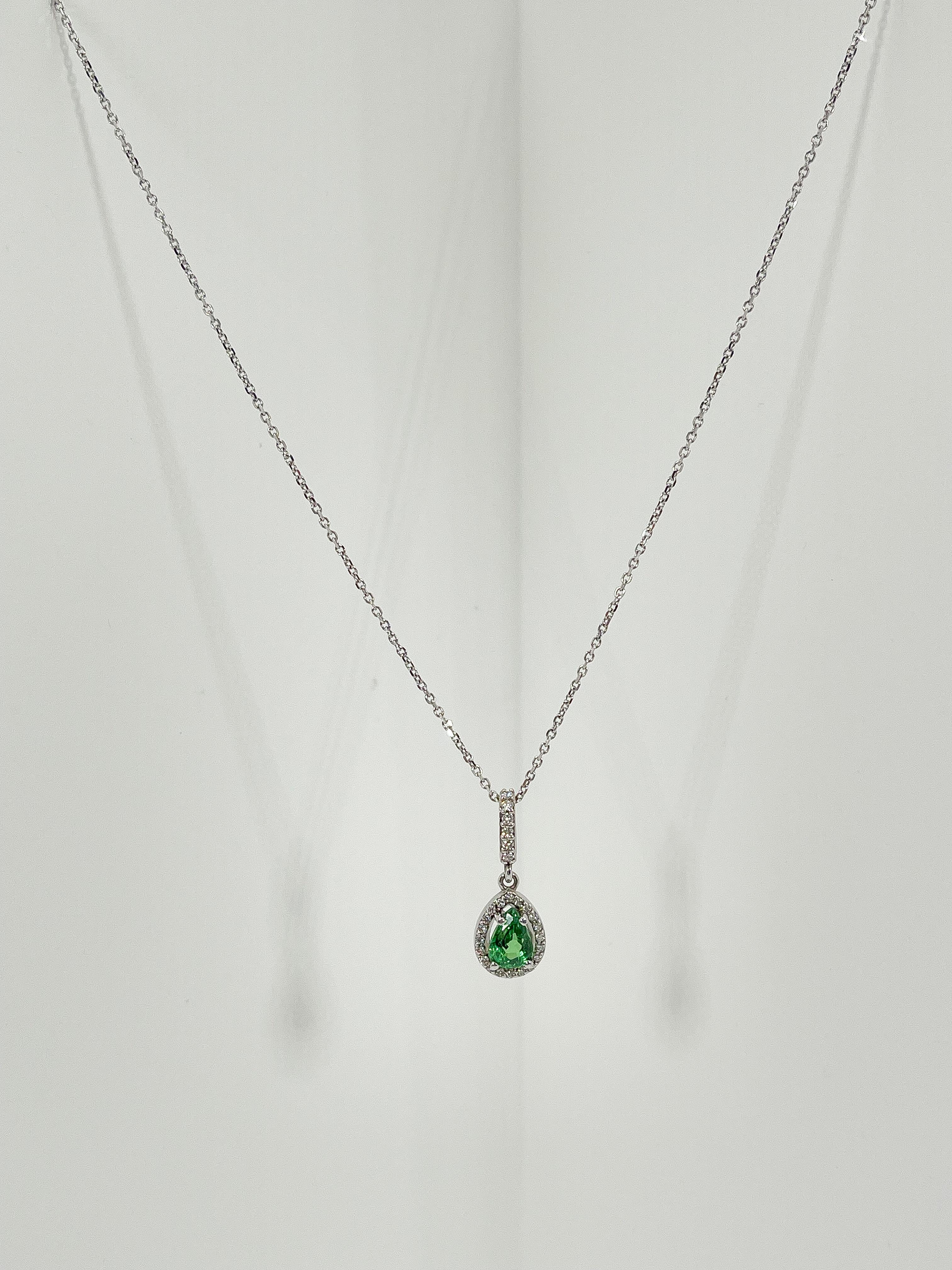 14k white gold 1 CT pear tsavorite and diamond halo necklace. All diamonds are round, the length of the necklace is 18 inches, the pendant measures 8mm x 10mm without bail, has a lobster clasp to open and close, has a total weight of 3.2 grams.