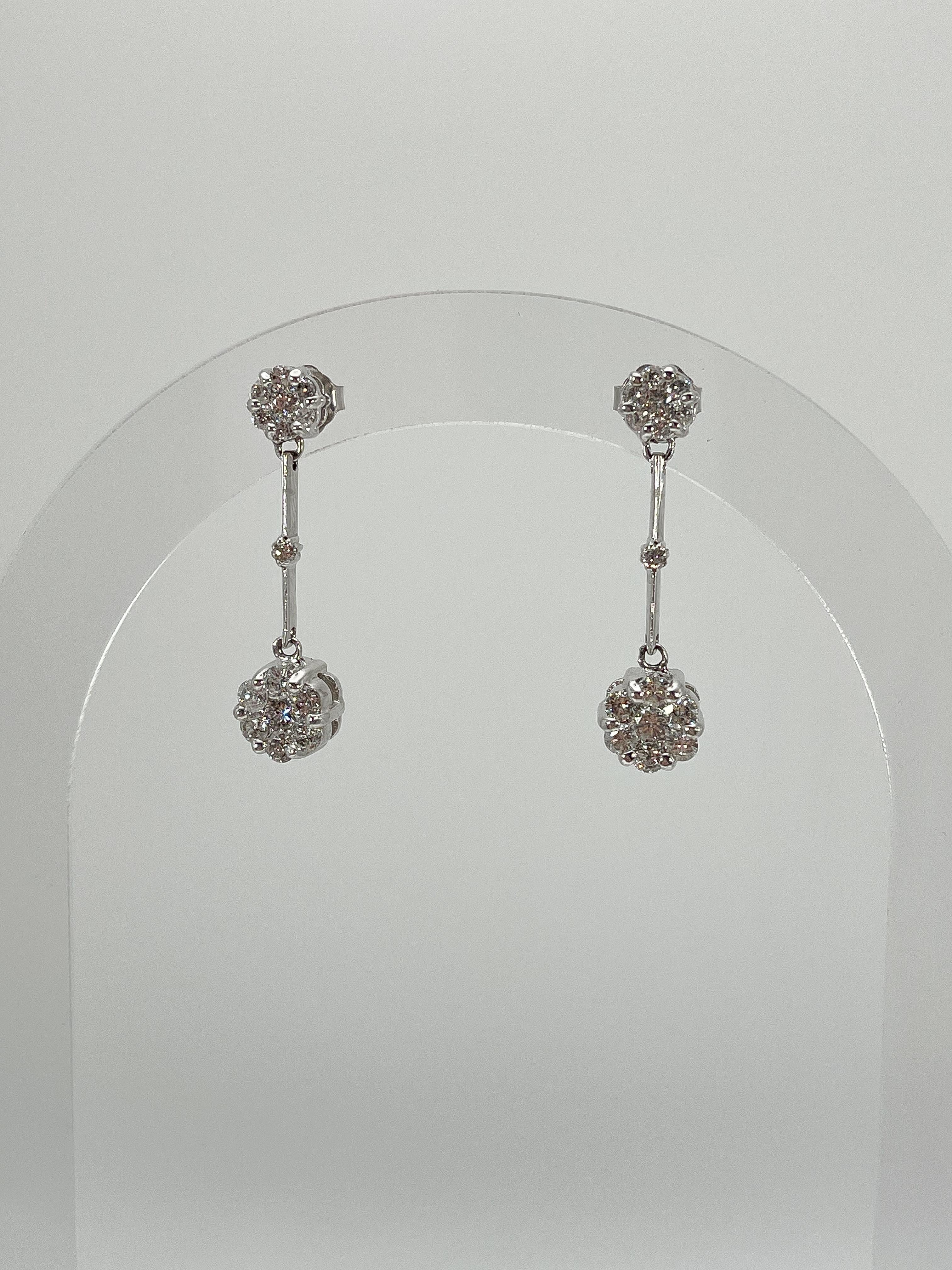 14k white gold 1 CTW diamond drop cluster earrings. These earrings have one cluster at the top, a diamond in the center, and one on the bottom. The length of these earrings have a length of 29 mm, a width of 7.8 mm, and a weight of 4.6 grams. 