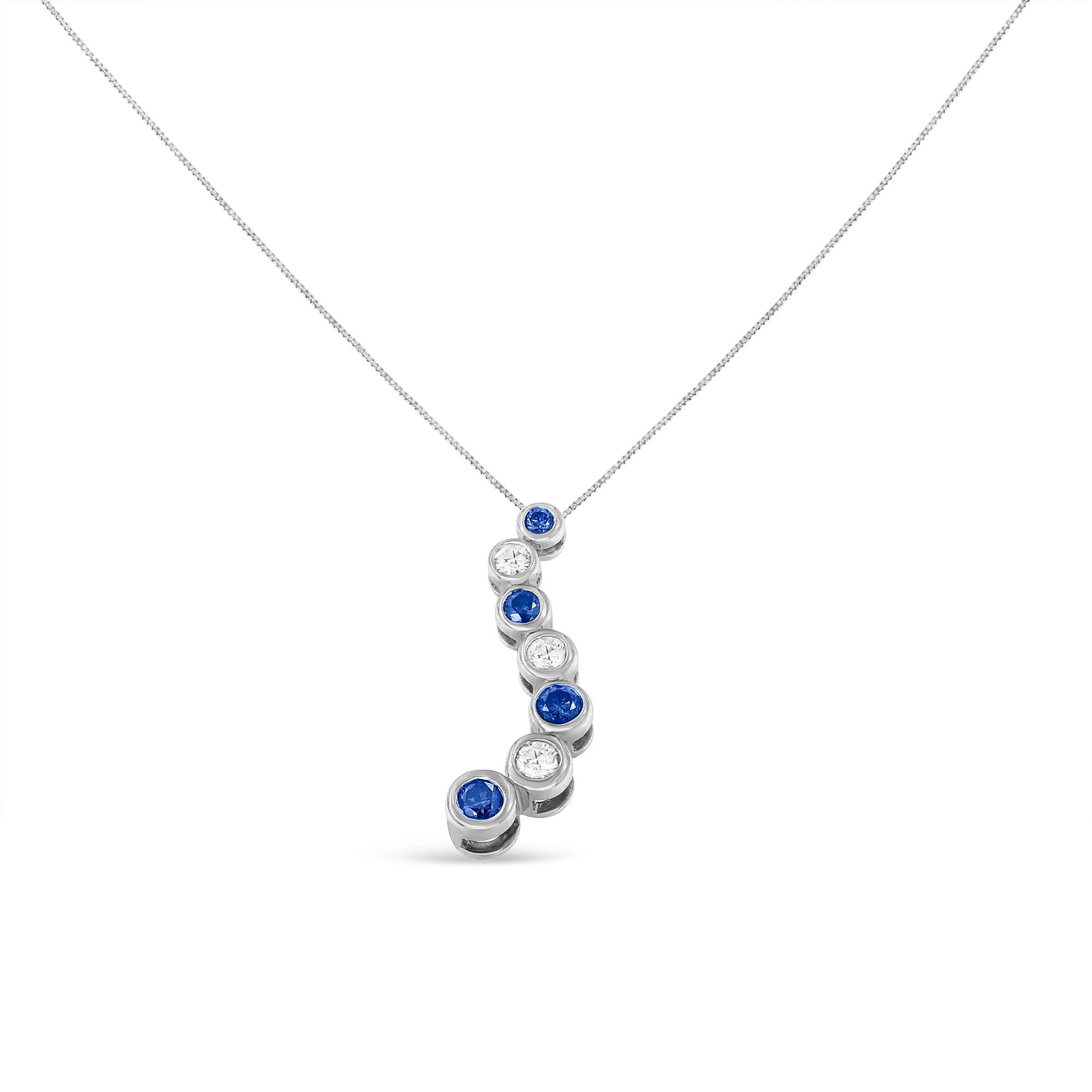 A diamond and white gold necklace. The necklace features 7 diamonds, including four treated blue diamonds, bezel set in 14 karat white gold. Together the diamonds weigh 1 carat. The diamonds are affixed to a box chain with a spring ring clasp. This