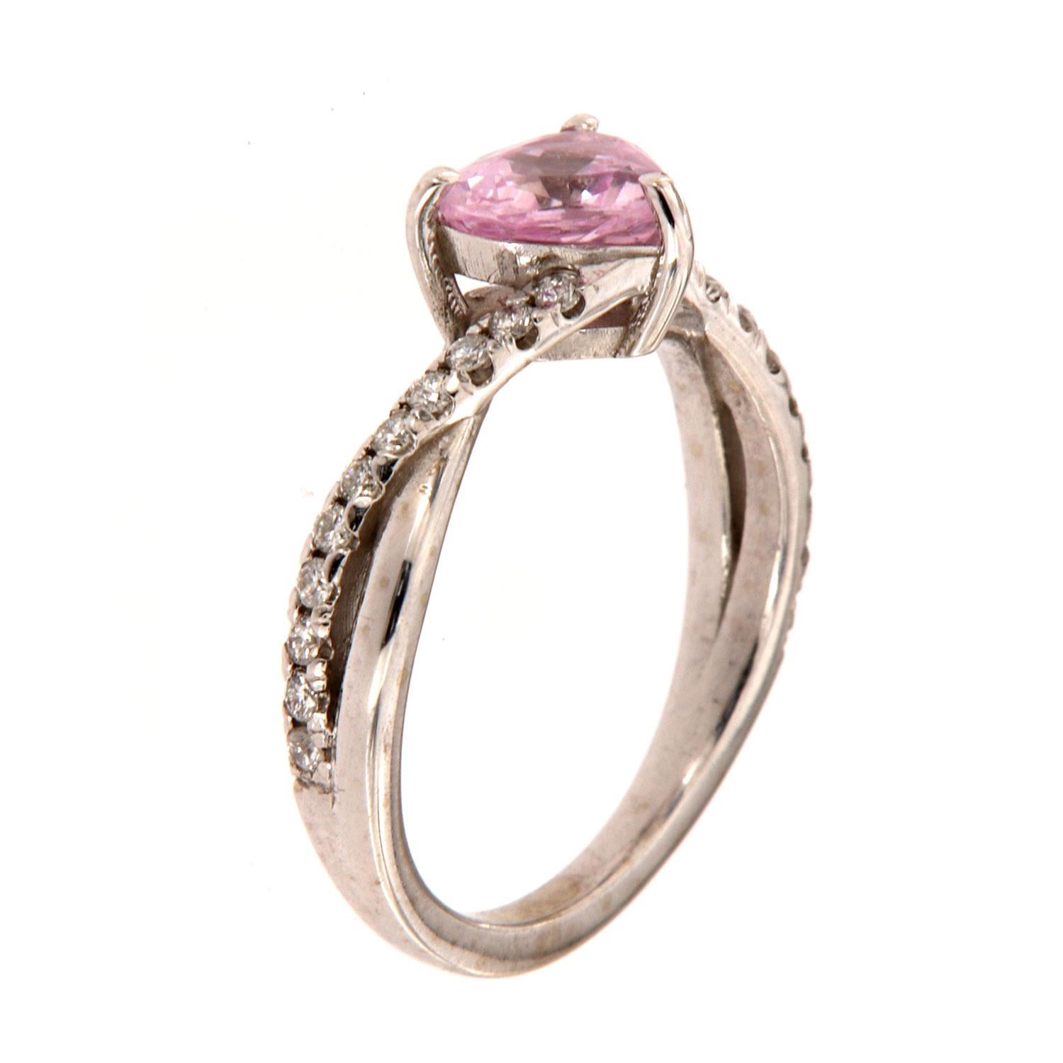This ring features a 1.00 - carat Heart-Shape Non-Heated Sri-Lankan Sapphire three-prong set.  Two rows of diamonds wrapped around the Sapphire complete this delicate ring.  The diamond weight on the ring is 0.21 Carat.
The Sapphire exhibits Pinkish