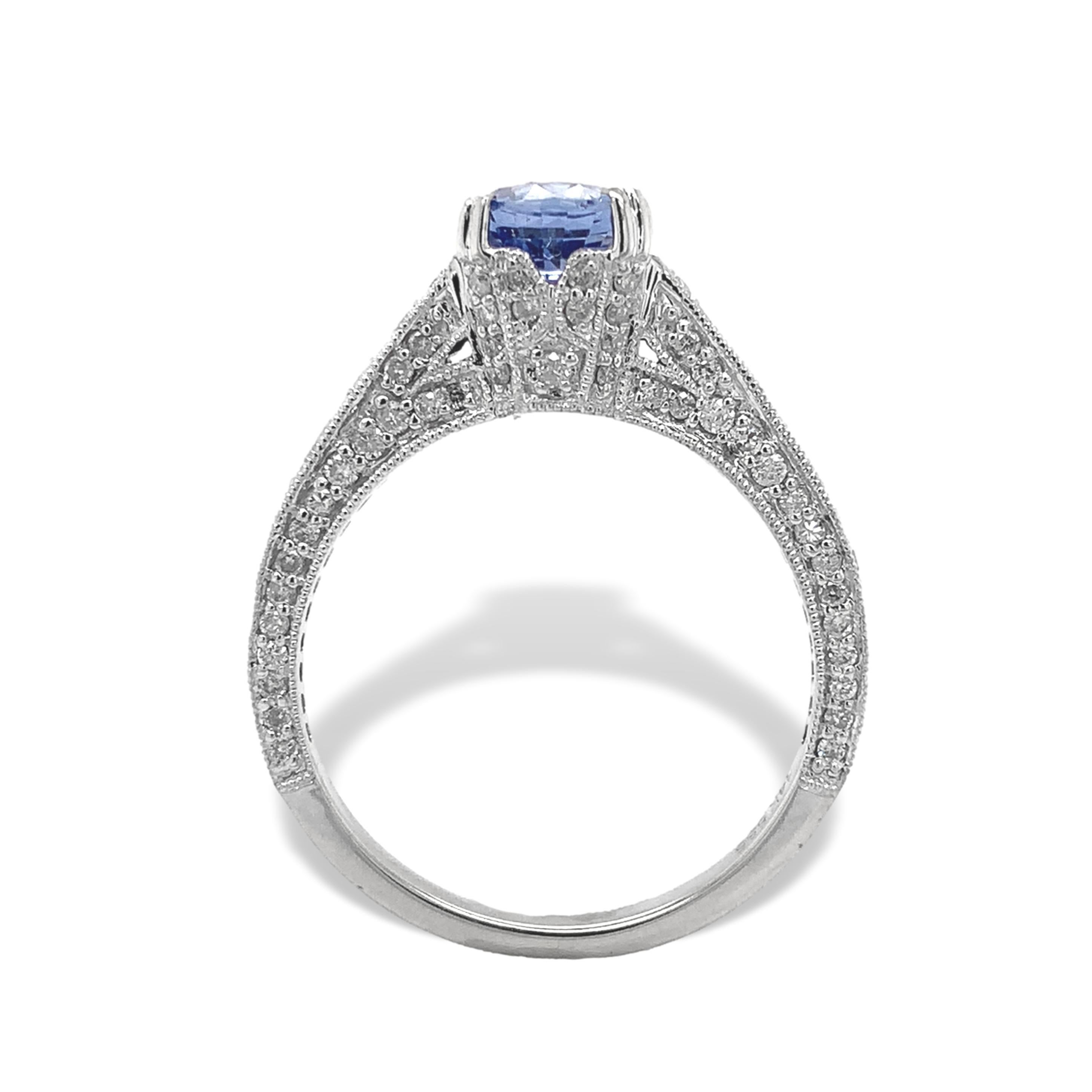 Anello in oro bianco 14K con zaffiro blu e diamante. L'anello presenta un autentico zaffiro blu rotondo taglio brillante estratto in terra. Misura circa 6 mm e pesa 1,15 carati. Lo zaffiro è di colore blu medio leggermente violaceo. La montatura è