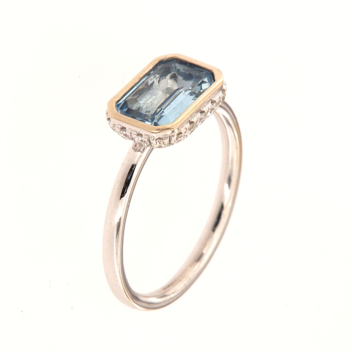 This 14k White gold delicate ring features a 1.23 Carat Blue Aquamarine emerald cut bezel set East-West style. Sixteen (16)Brilliant round diamonds are micro-prong set in a hidden halo on the crown to create the sparkle look every woman is looking
