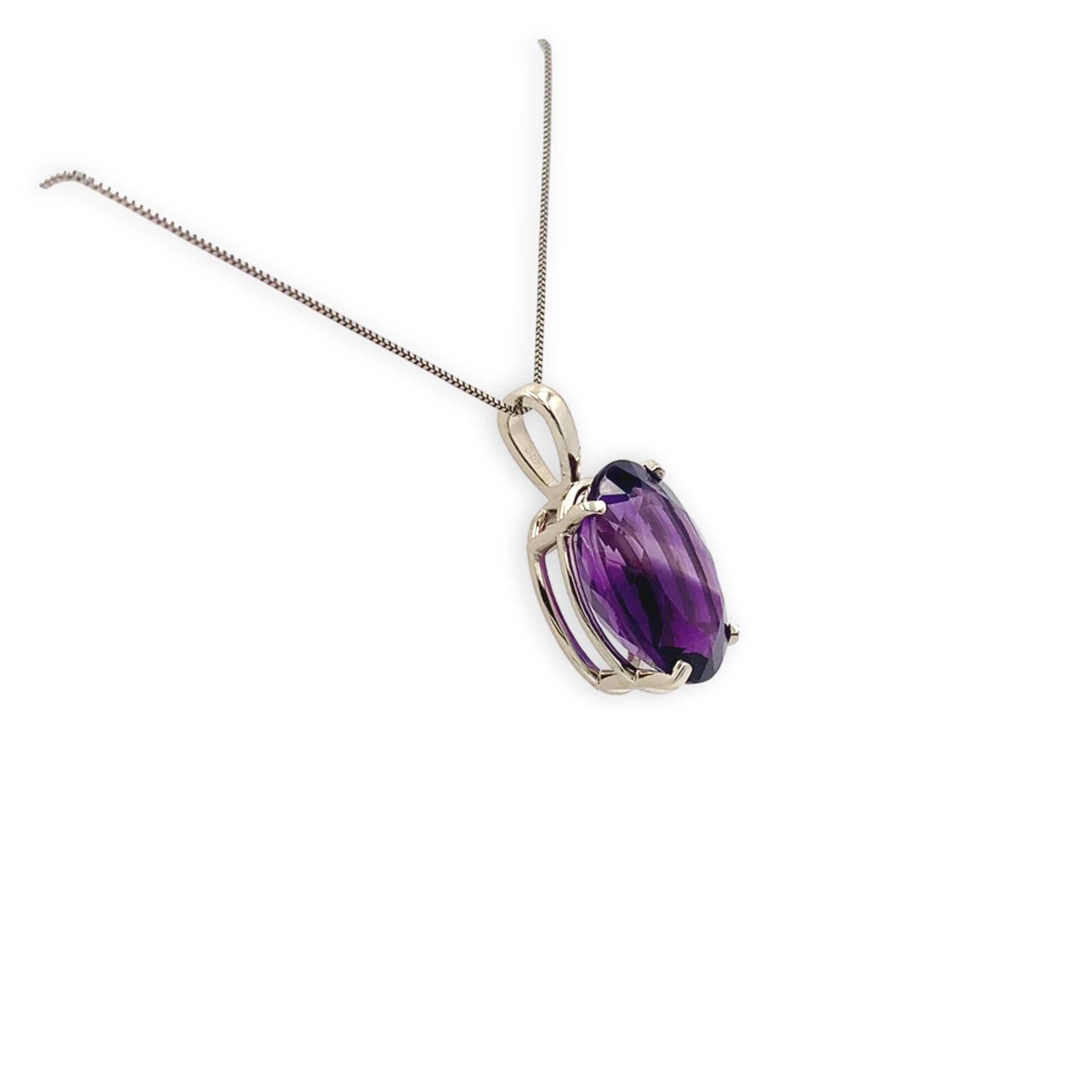Pendentif en or blanc 14 carats orné d'une améthyste de taille ovale. L'améthyste a une belle couleur pourpre royal. L'améthyste pèse 12,52 carats et mesure environ 18 mm x 13 mm. Le pendentif mesure 1