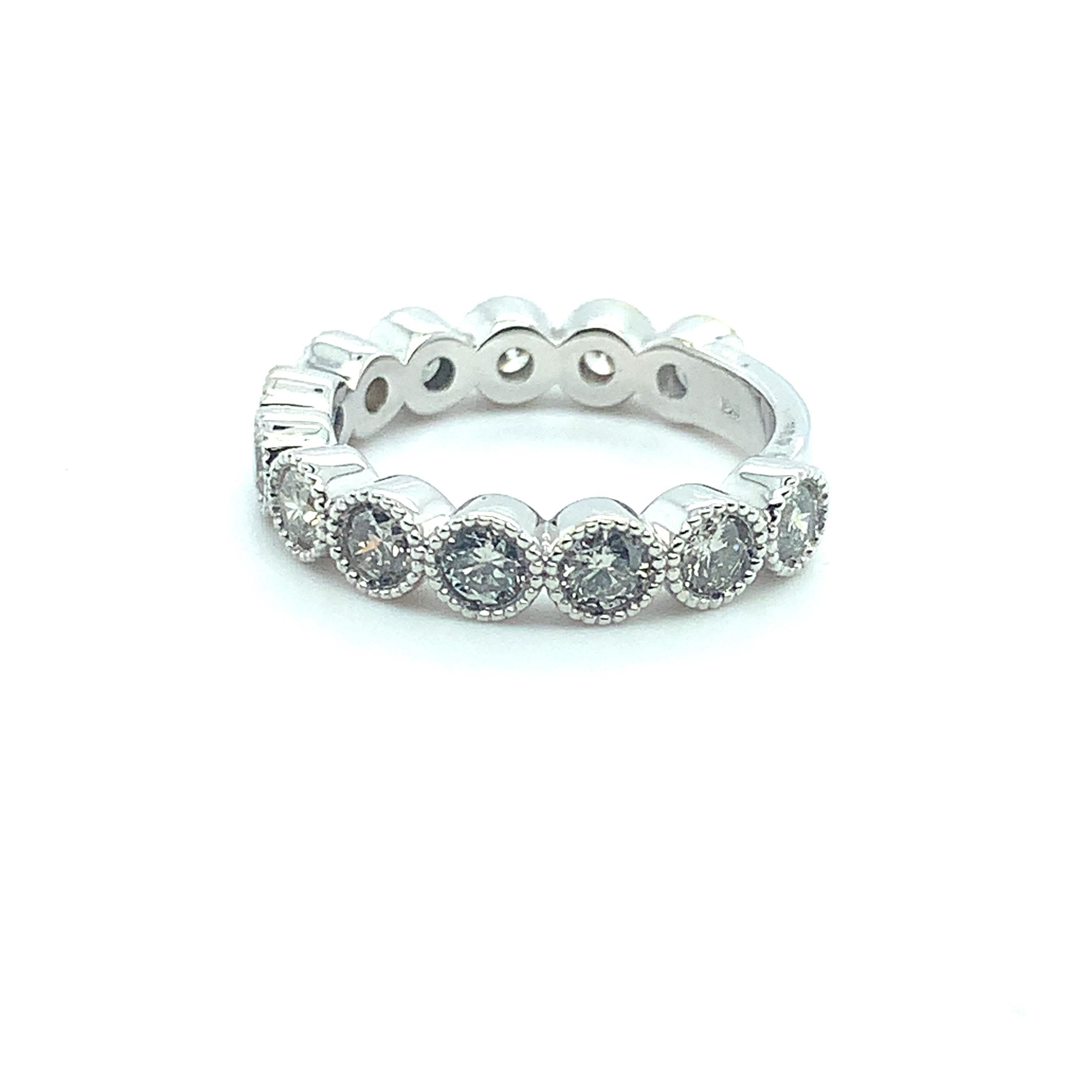 Stunning 14K white gold diamond wedding band featuring 13 round brilliant cut diamonds weighing 1.43 carats total. The diamonds are set in bezels with a milgrain edge. The diamonds go 3/4 around the ring, so it looks like an eternity band but does