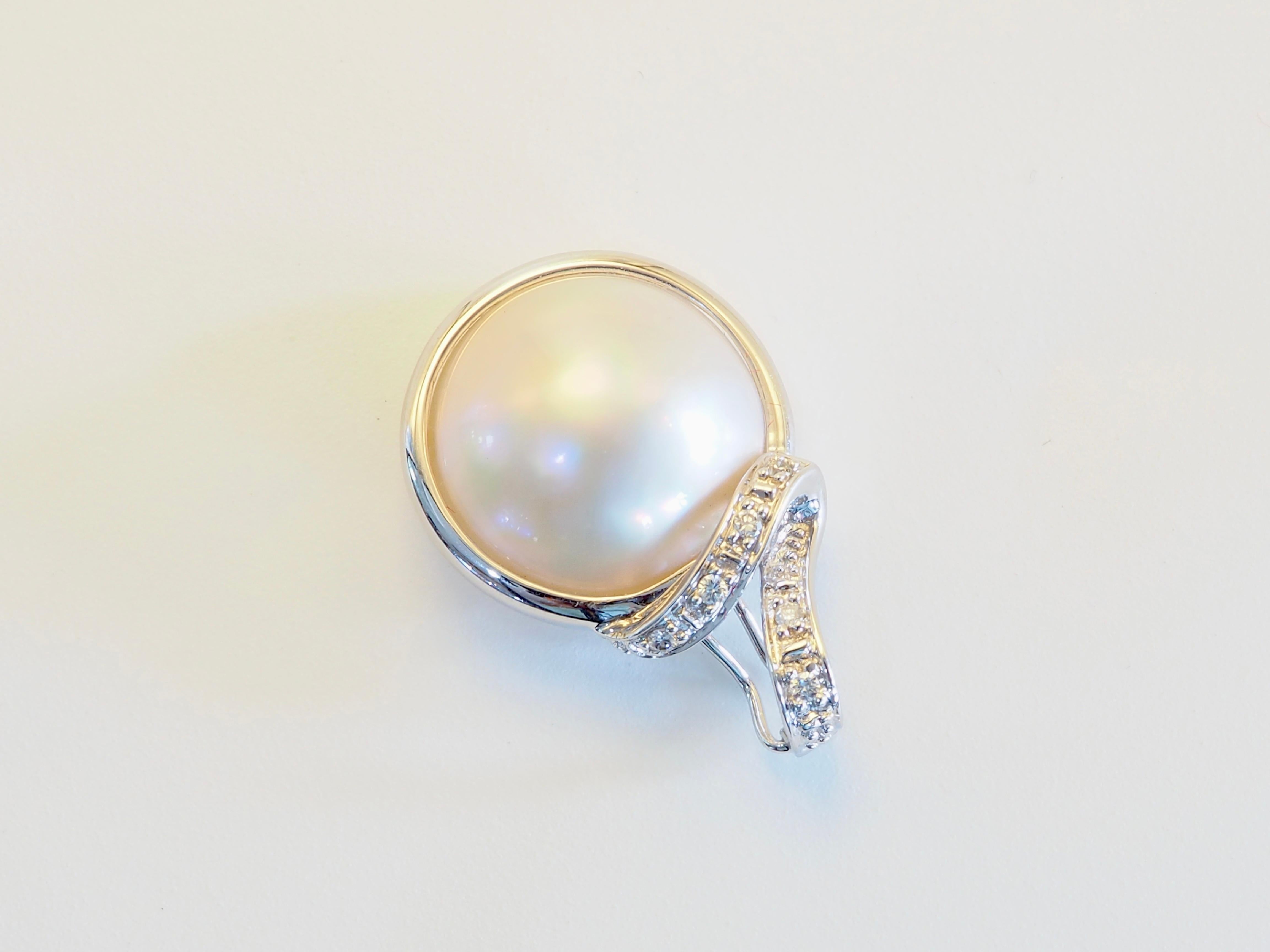                   Eleva la tua collezione con questo squisito ciondolo, realizzato a mano in oro bianco massiccio 14K e con una luminosa perla Mabe da 14,5 mm. Rever per la sua cupola liscia e il suo bagliore iridescente, la perla è cullata in una